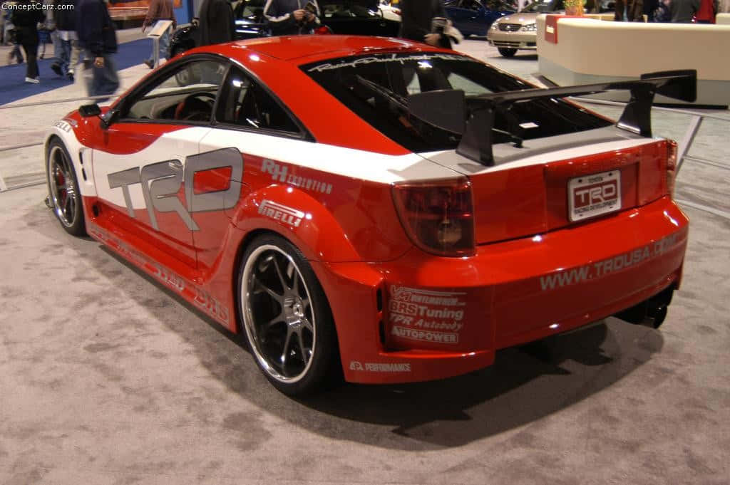 紅色豐田Celica TRD運動車展示 壁紙 — 一輛鮮豔的紅白TRD調校跑車，配備大型後尾翼，在車展上展出。