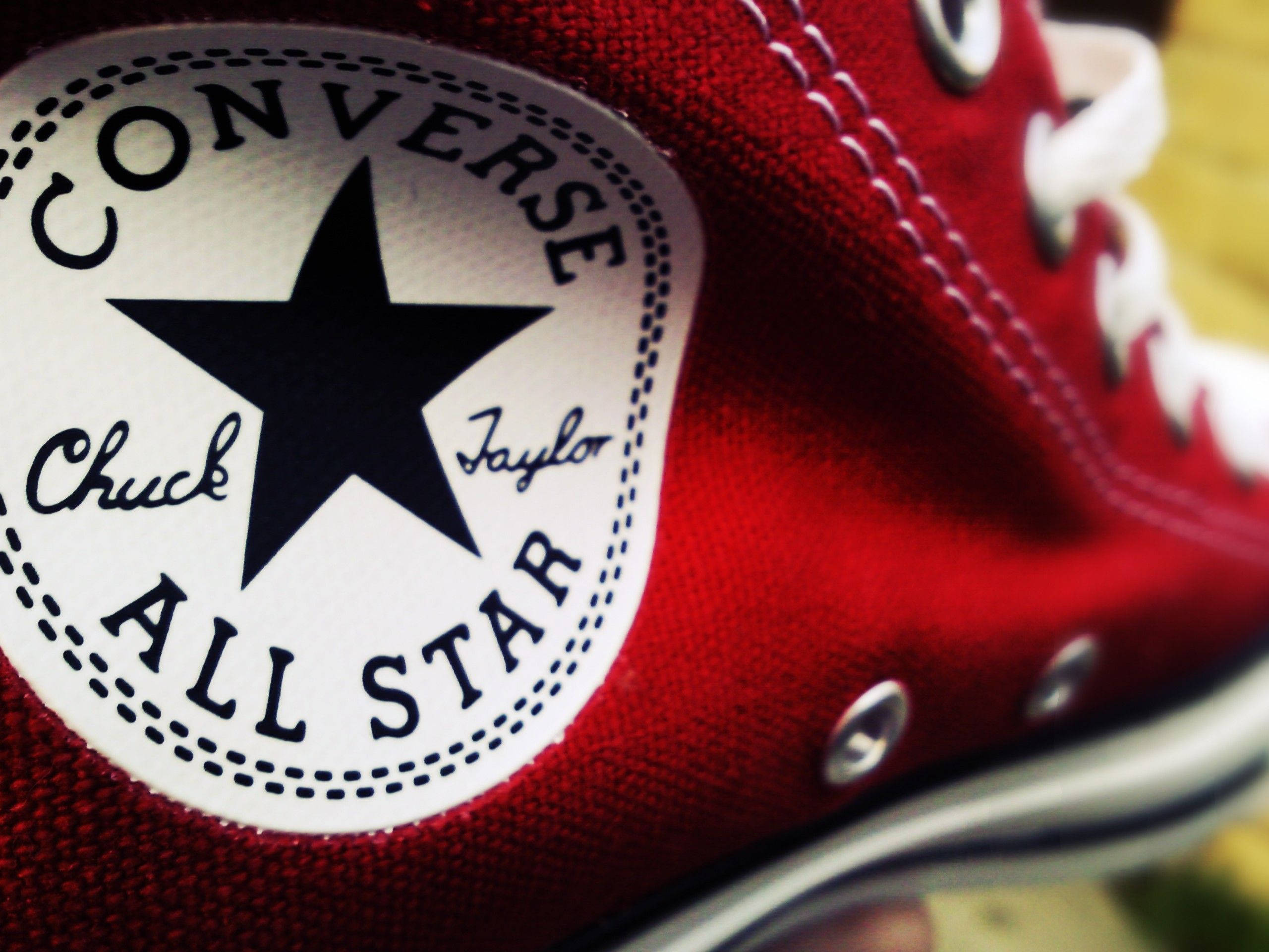 紅色運動鞋匡威標誌 壁紙 — 紅色Converse Chuck Taylor All Star運動鞋的特寫，突顯標誌性的星星標誌和白色鞋帶。