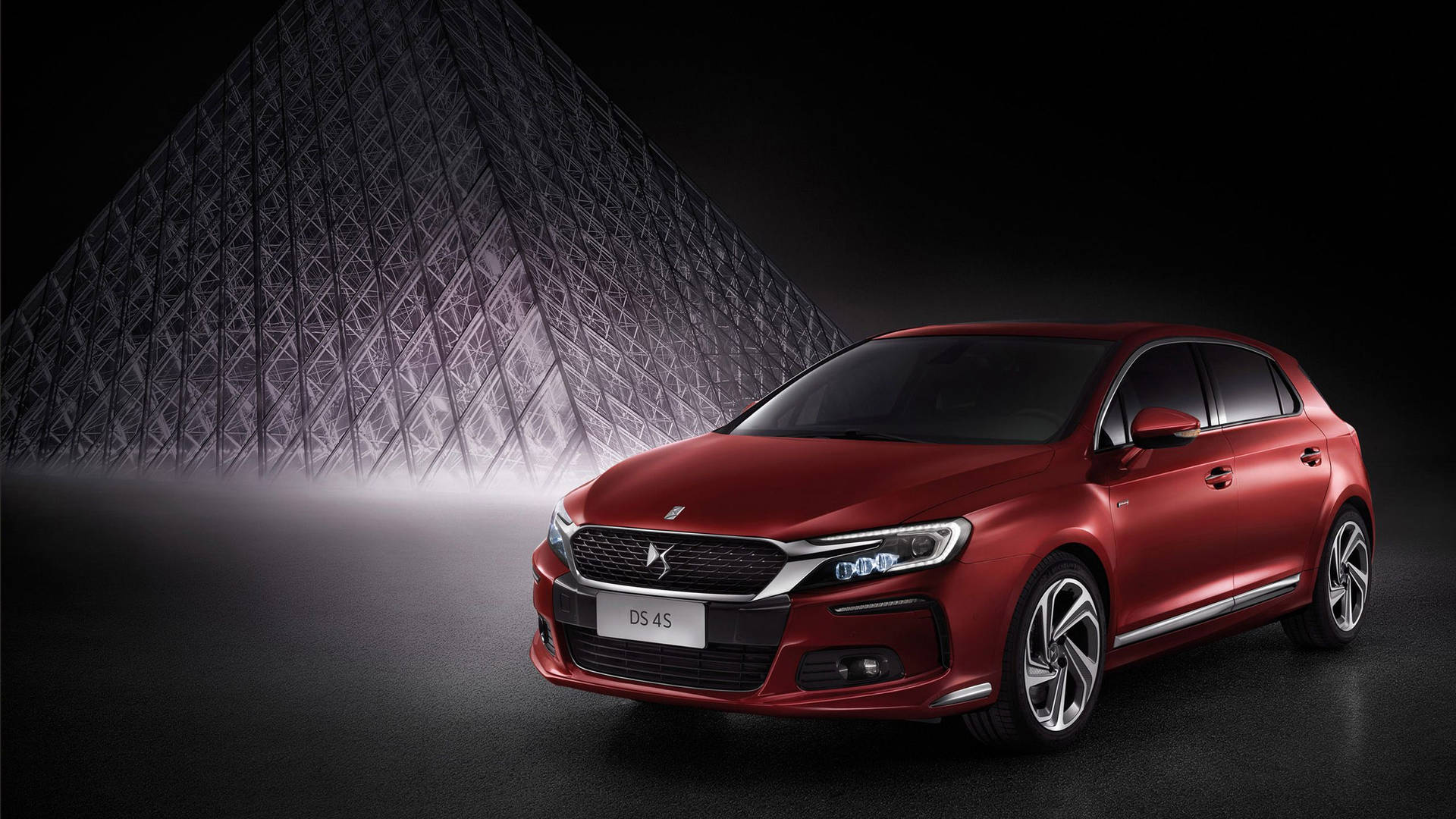 紅色 DS 4S 汽車放置在羅浮宮金字塔前，處於黑暗的工作室環境中。