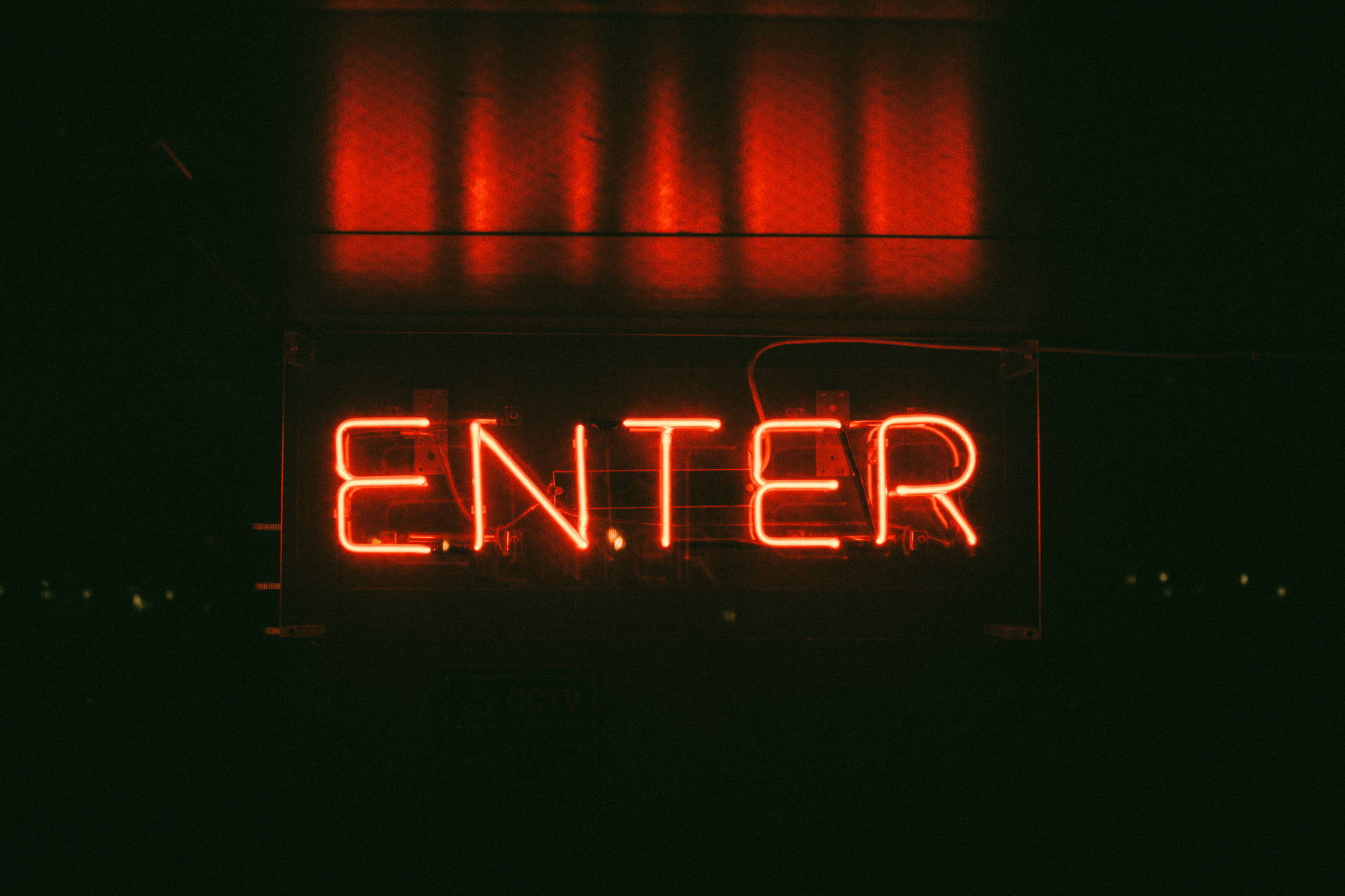 一個紅色霓虹燈 ENTER 在黑暗中發光，上方有反射。