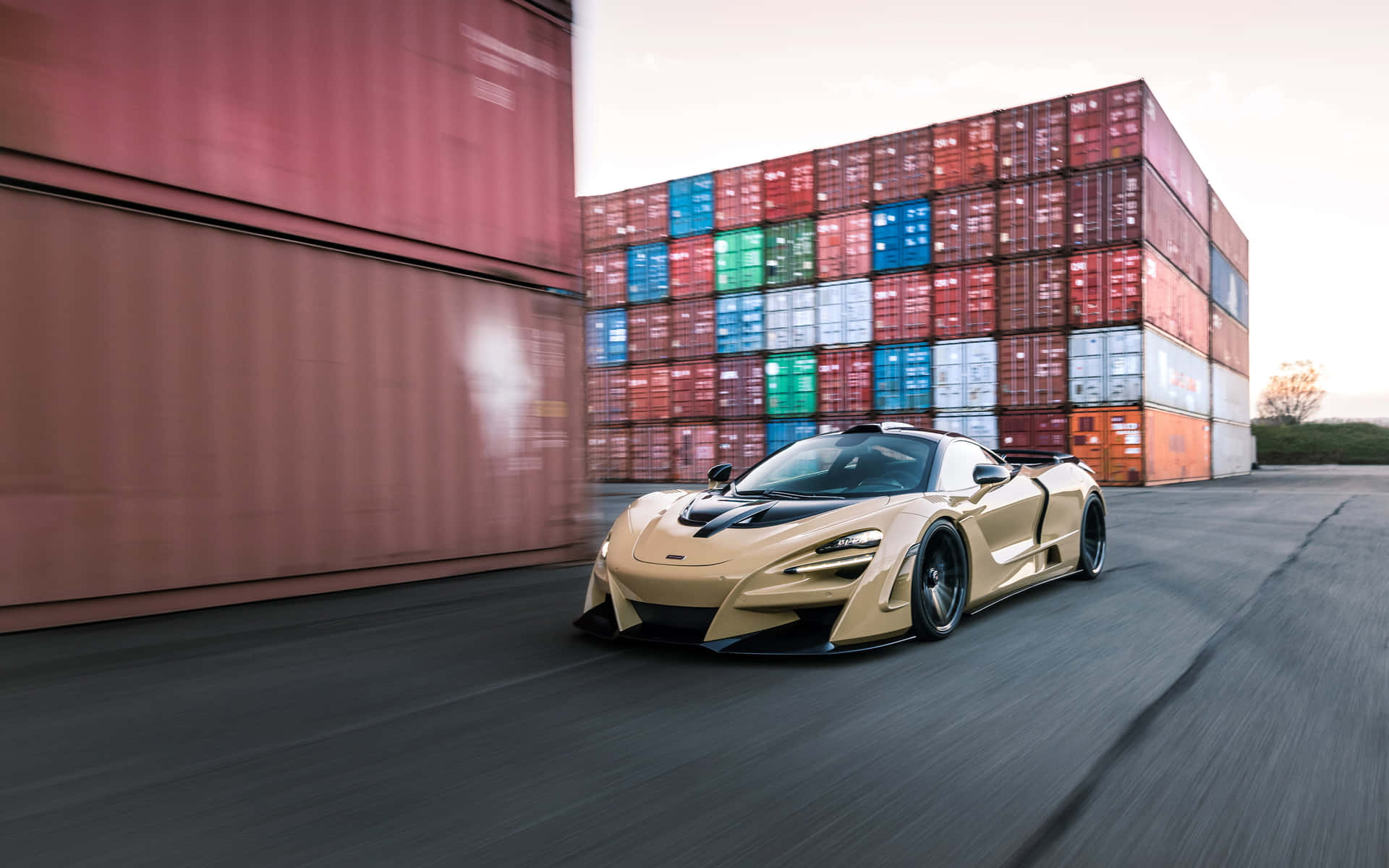 金色跑車在日落時分高速駛過色彩繽紛的貨運集裝箱。