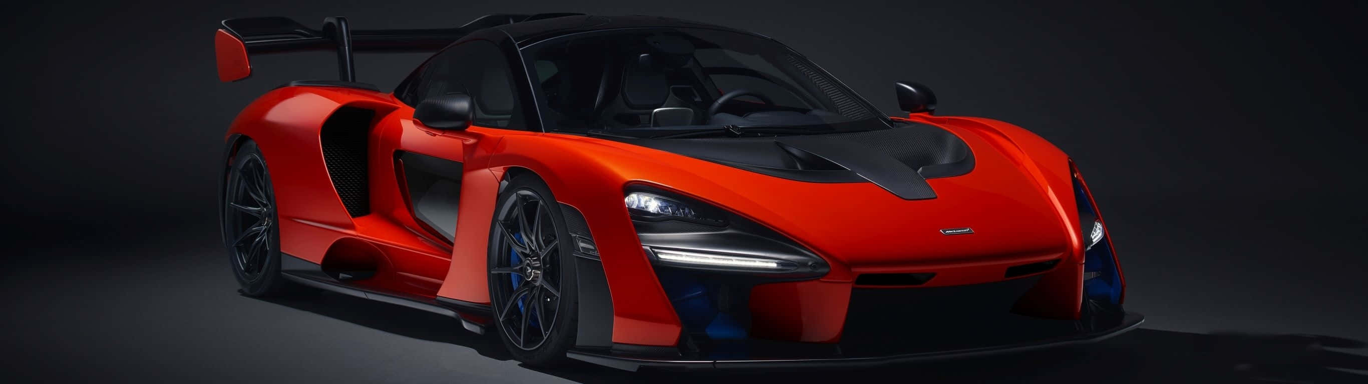 紅色McLaren Senna超級跑車，帶有黑色飾件和藍色制動卡鉗，在工作室燈光下。