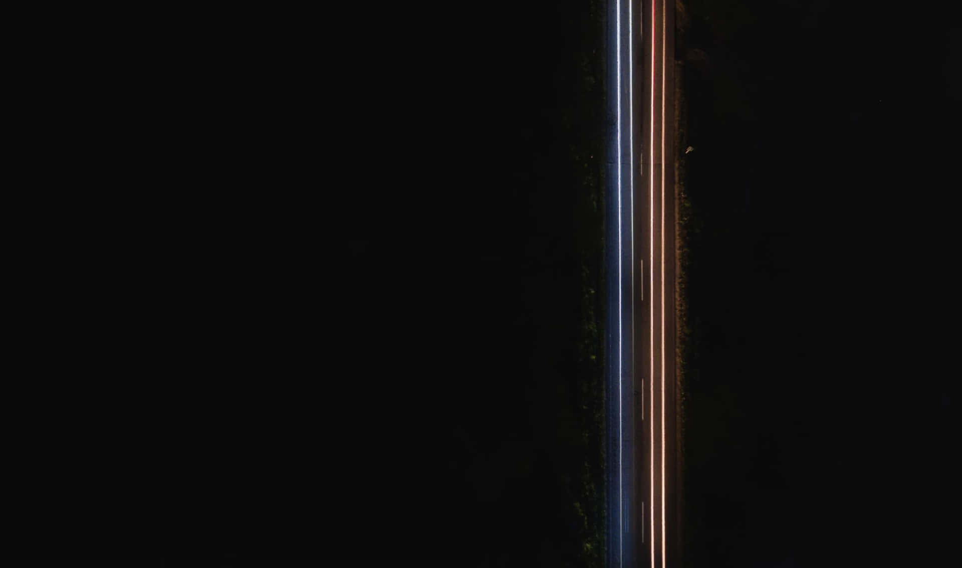 夜間空中俯瞰黑暗道路上汽車的光軌。