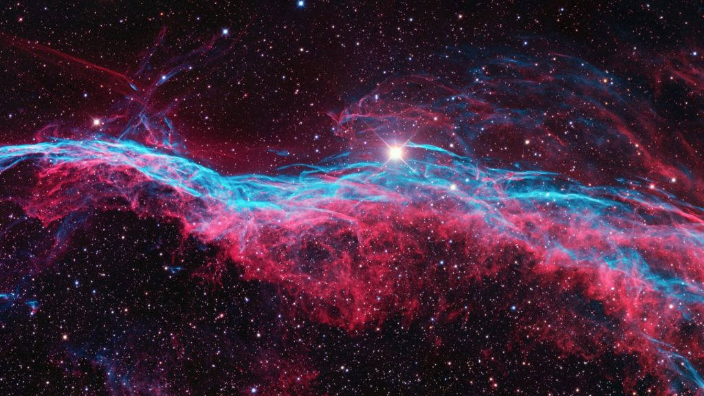 紅藍宇宙的太空電腦壁紙 壁紙 — 一個宇宙星雲在鮮紅色和電藍色中旋轉，背景是星場，一顆明亮的中央恆星照亮了宇宙塵埃。