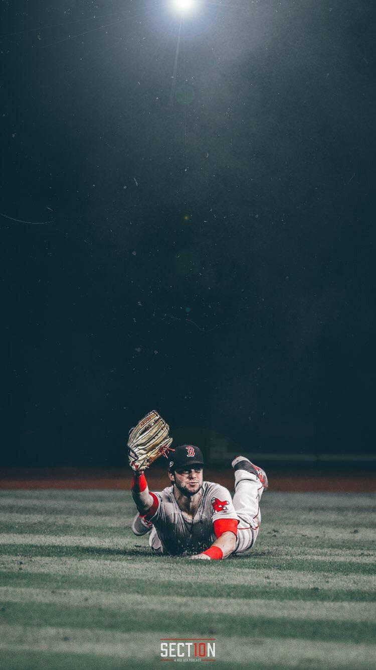棒球運動員在夜間球場燈光下飛撲接球。