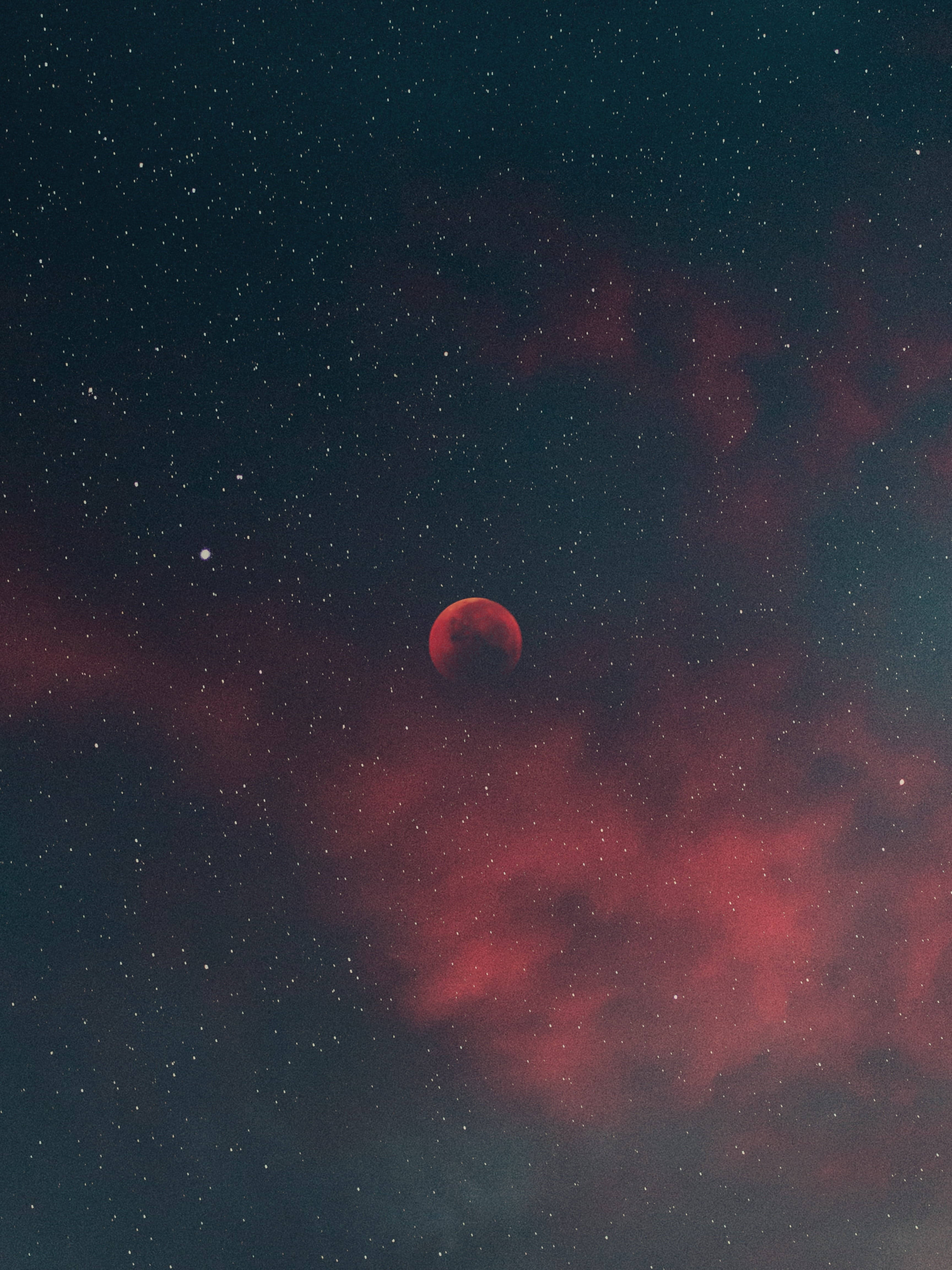 紅雲月光4K 壁紙 — 在深邃的宇宙夜空中，一輪血紅色的月亮在旋轉的深紅色星雲和閃爍的星星之間發光。