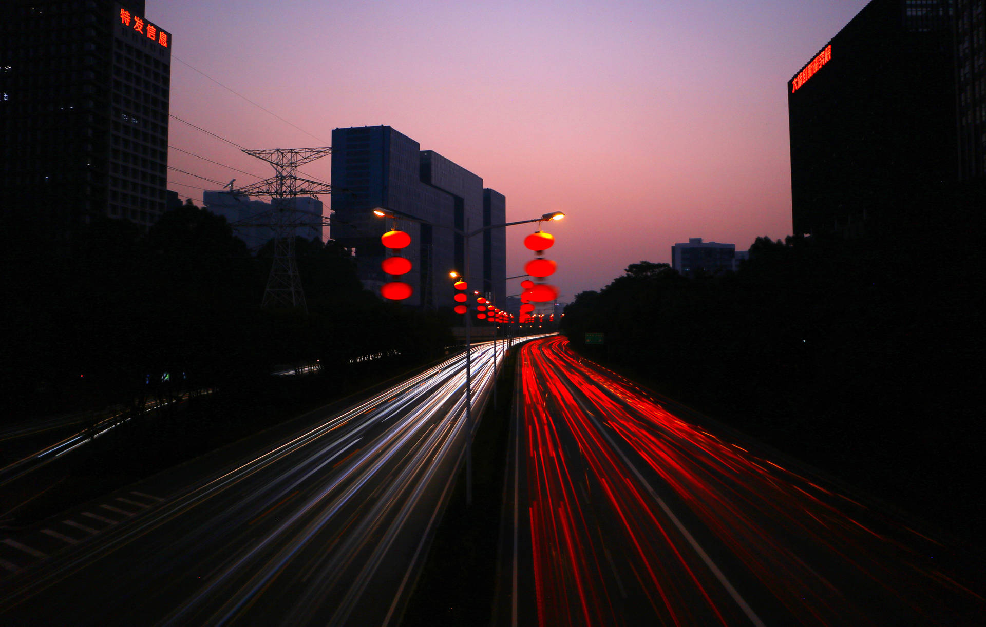 黃昏時分的城市高速公路，移動車輛的光跡和發光的紅色燈籠。