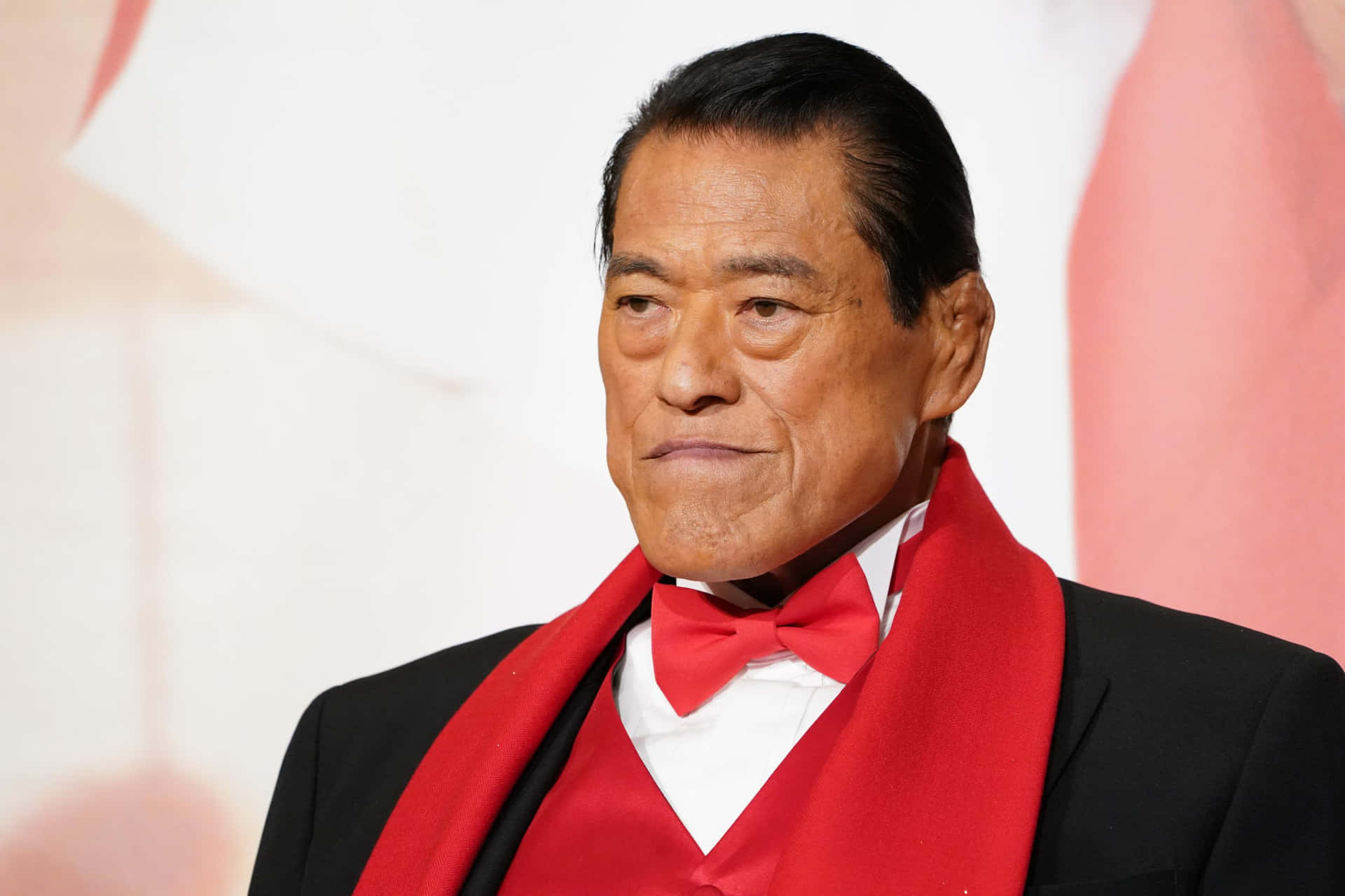 一位身穿黑色西裝和紅色領結、表情嚴肅的男士。