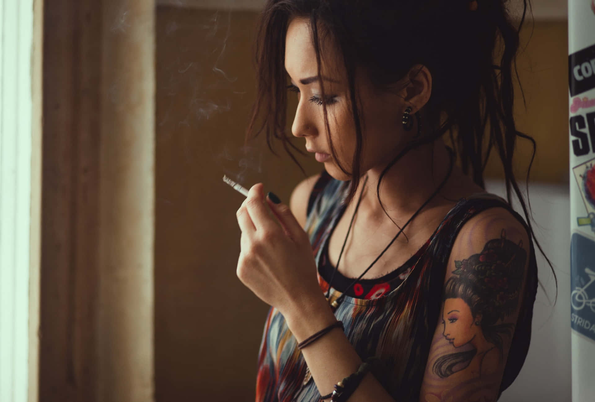 有紋身女人在室內窗邊抽煙