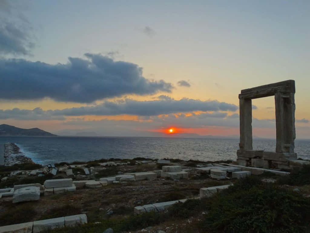 古老石頭廢墟在黃昏時分框住海上的夕陽。