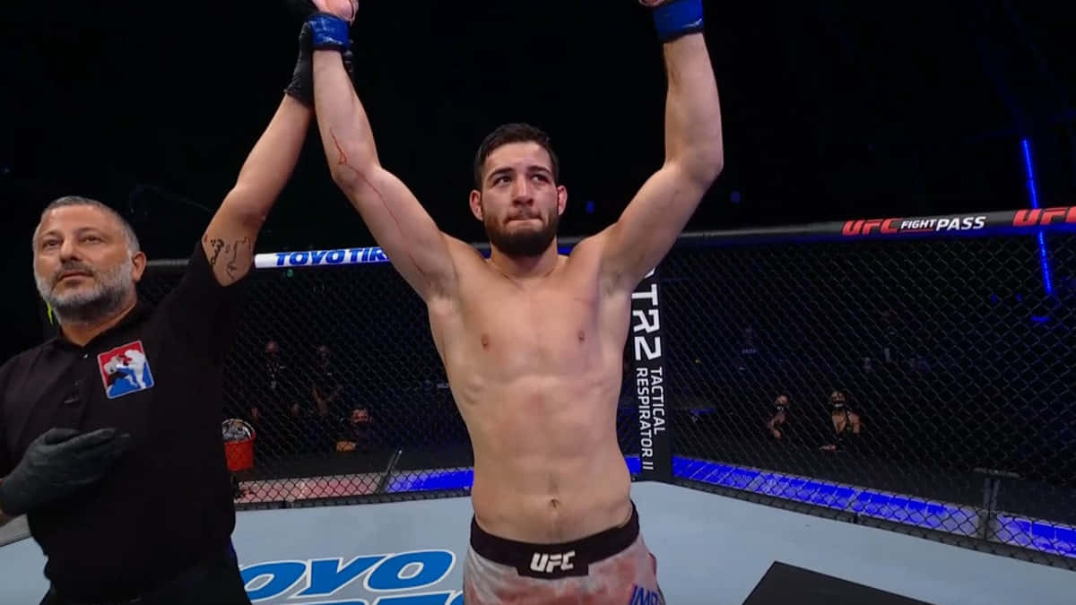 UFC拳手在八角籠中舉臂慶祝勝利。
