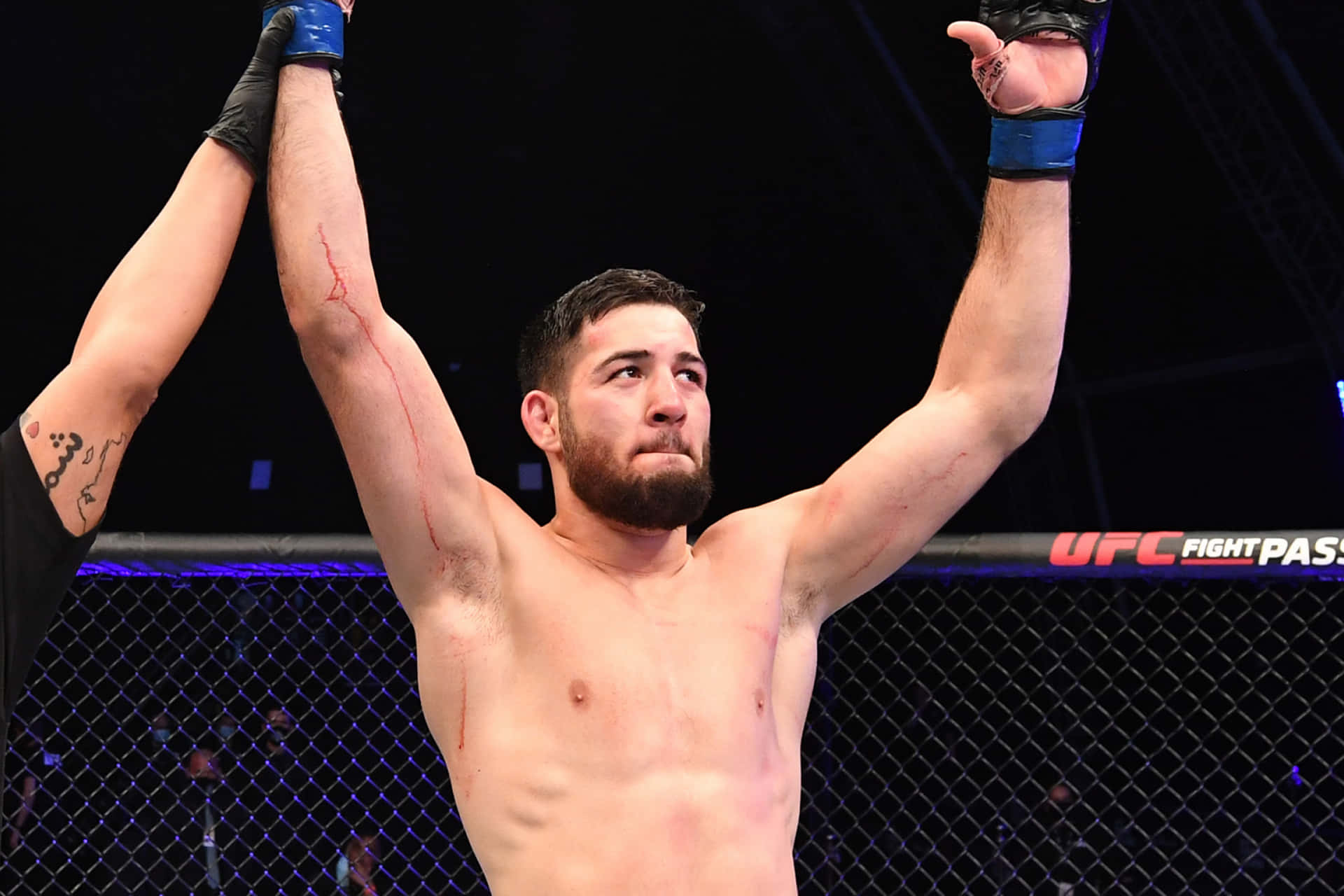 UFC鬥士在八角籠內高舉雙臂慶祝勝利。