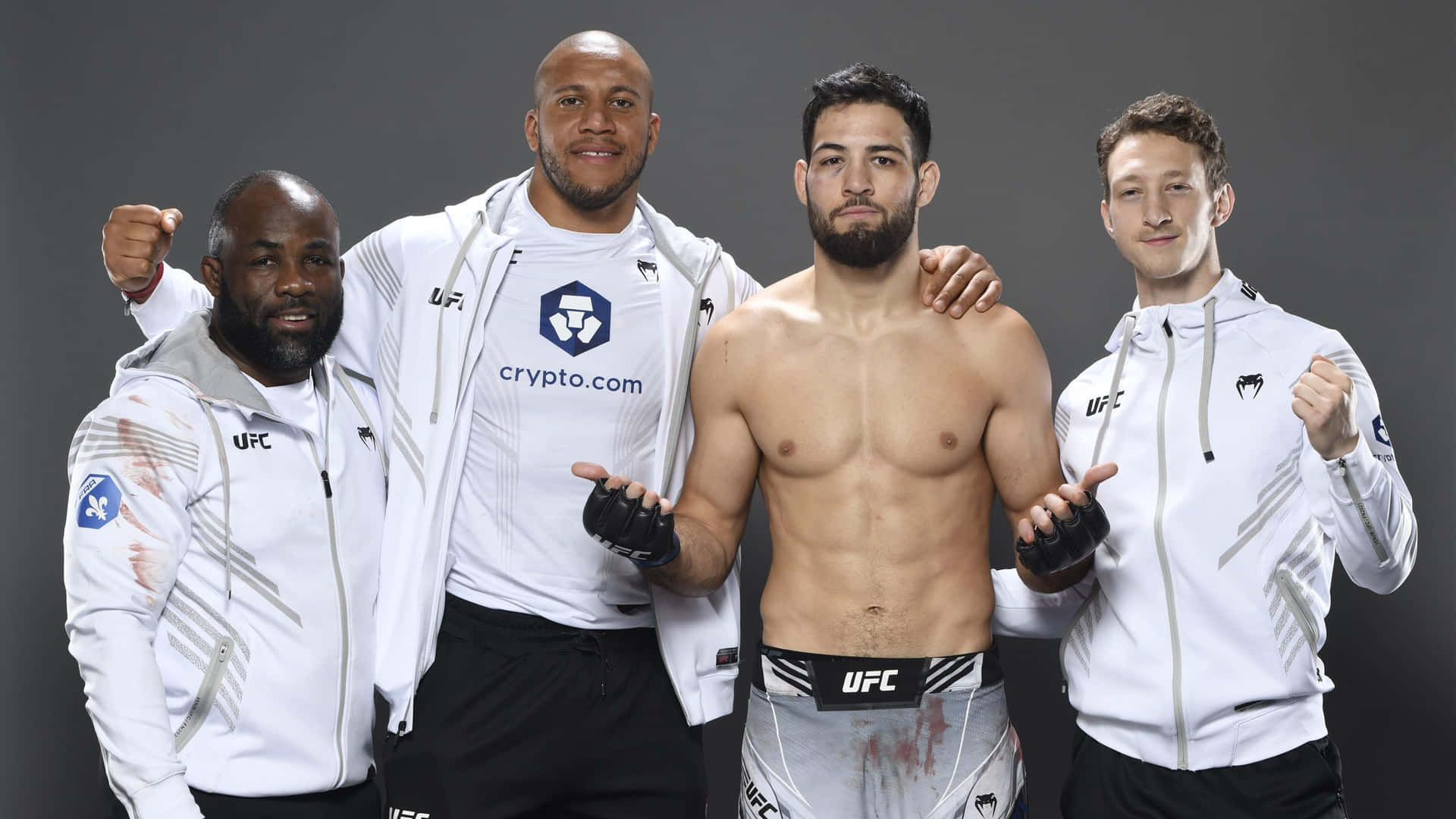 四位男性UFC拳手在攝影棚擺姿勢，中間一位赤裸上身。