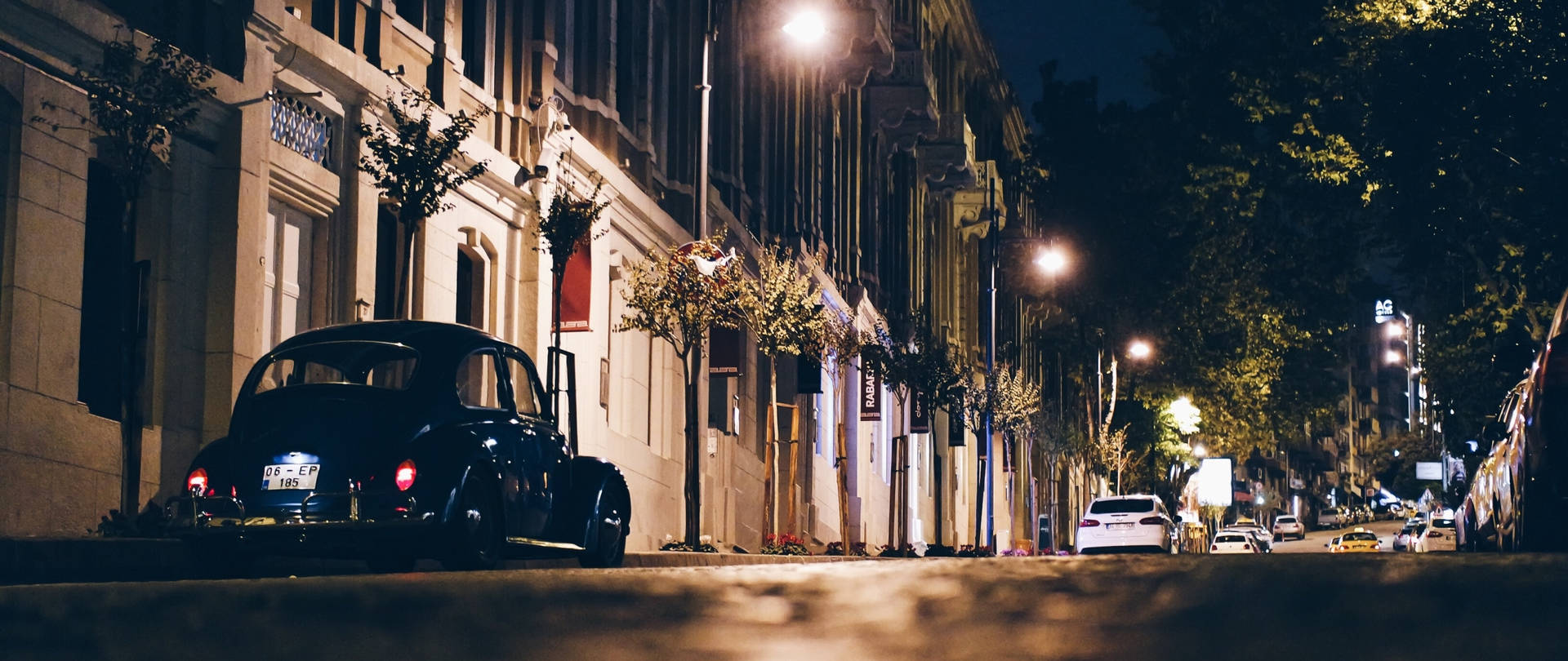 夜間停泊在照明城市街道上的復古黑色汽車。