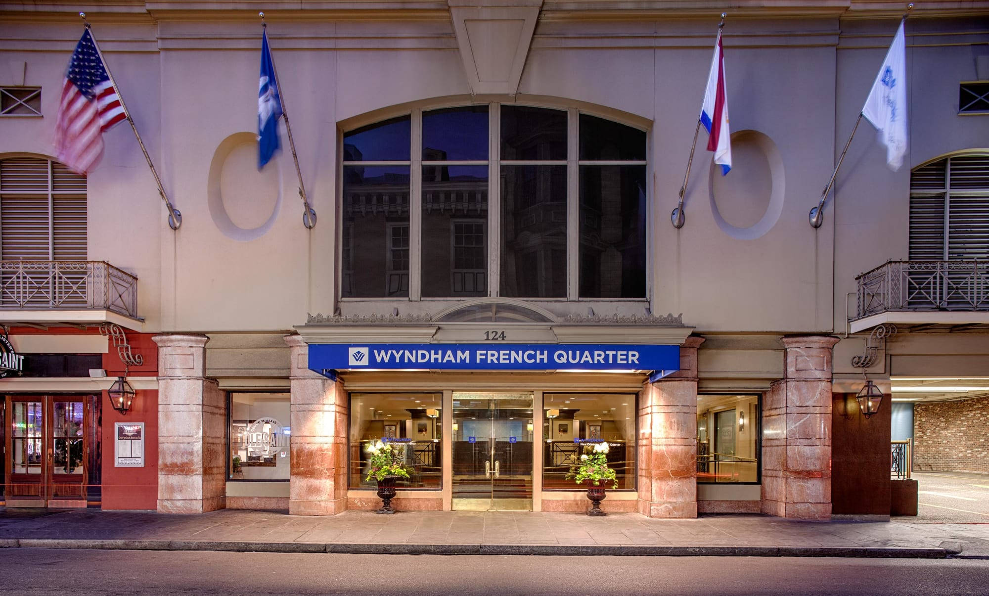 紐奧良法國區的維多利亞式 Wyndham 酒店 壁紙 — 黃昏時分，Wyndham French Quarter 酒店外牆，旗幟和溫暖的燈光照亮入口。