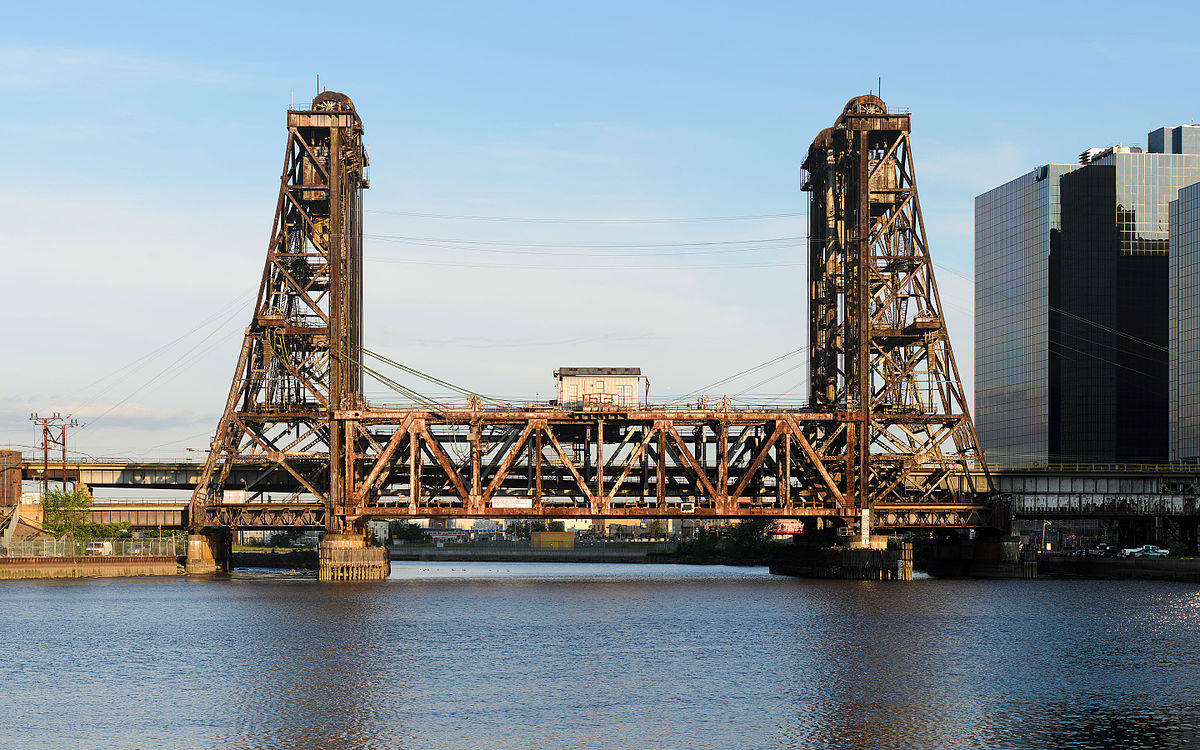 河上生鏽的鋼橋，背景有現代建築