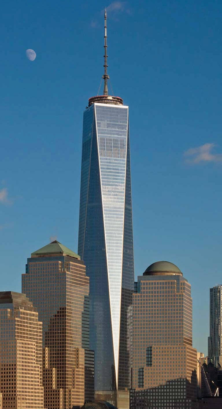 One World Trade Center摩天大樓，藍天中有月亮，周圍建築物沐浴在金色陽光中。