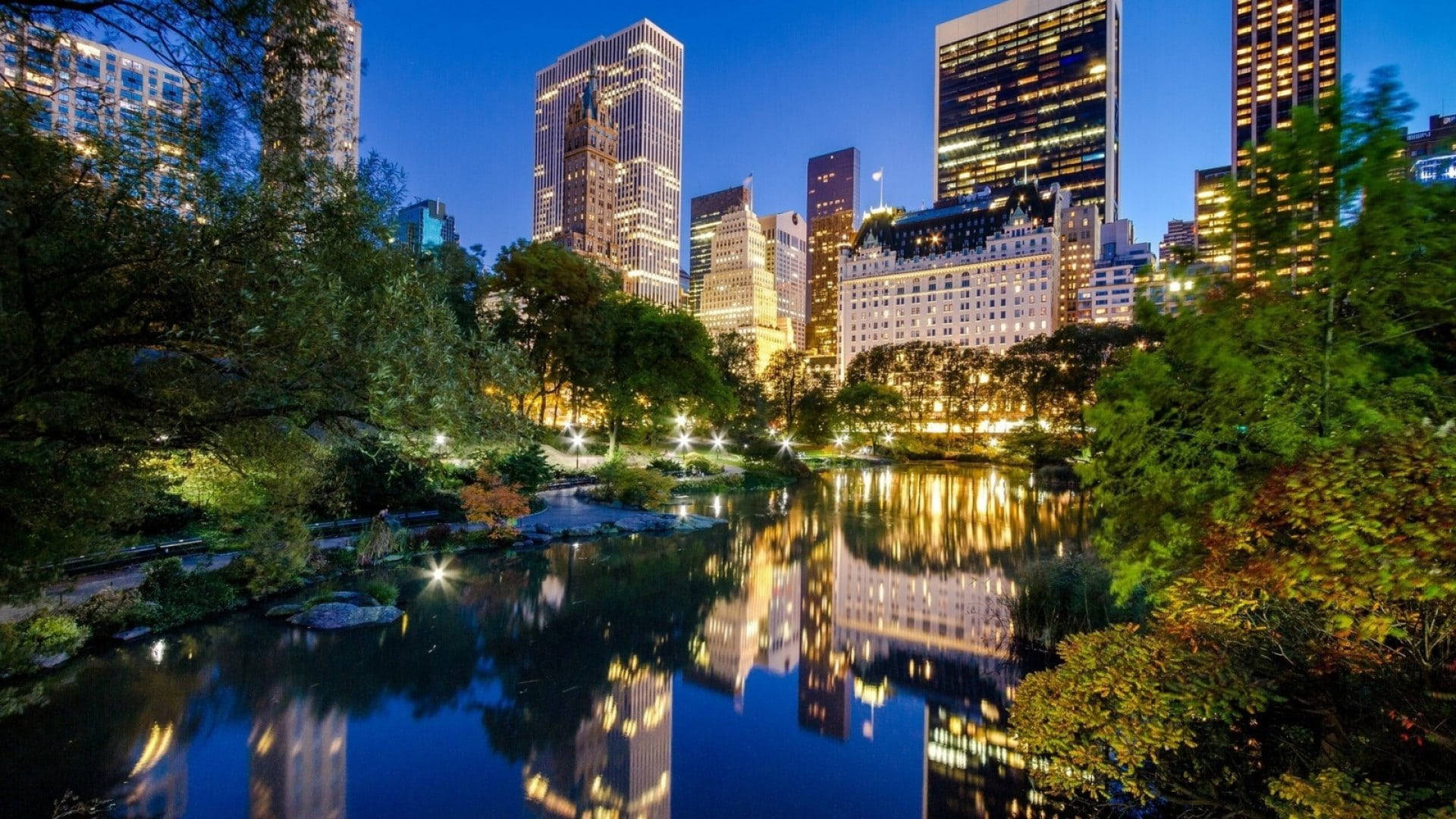 夜晚的中央公園，城市燈光倒映在水中。