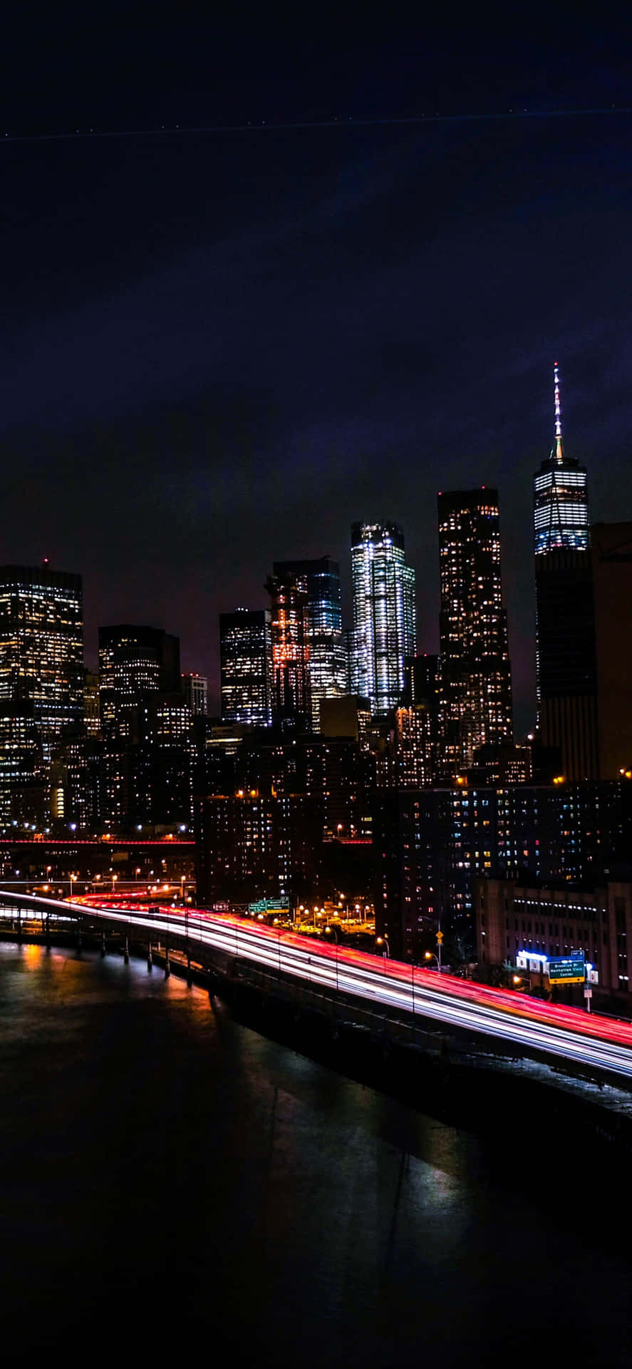 time lapse 桌布 壁紙 — 紐約充滿活力的夜景，閃爍的摩天大樓和在水面上劃過的紅色交通燈光軌跡。