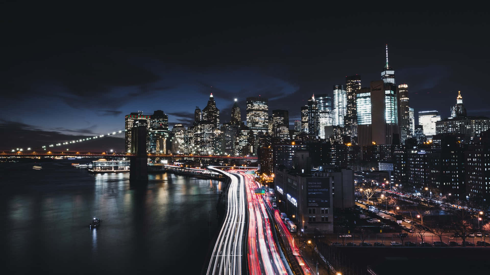 紐約城市夜景 壁紙 — 長時間曝光捕捉到流動的交通燈光和發光的摩天大樓照亮布魯克林大橋的夜景。
