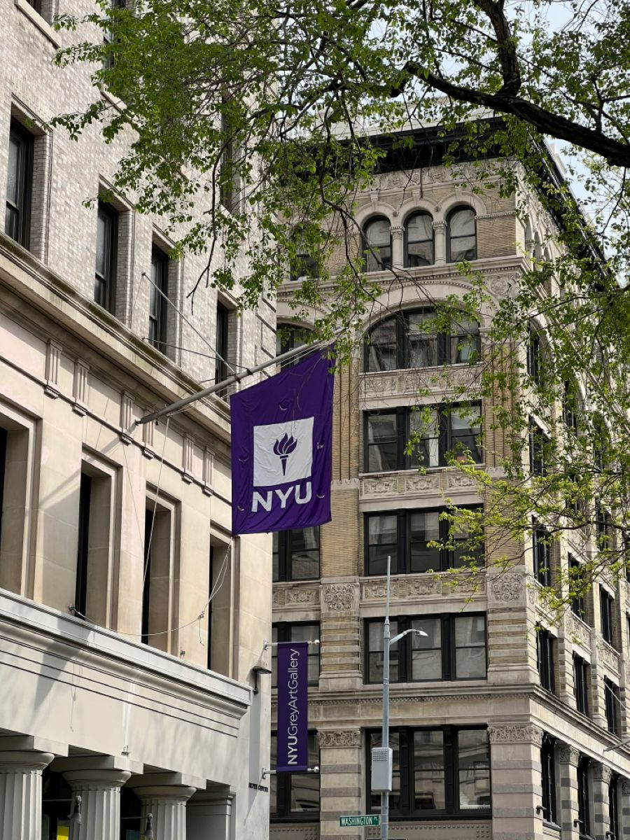 NYU橫幅掛在石建築之間，可見綠樹。
