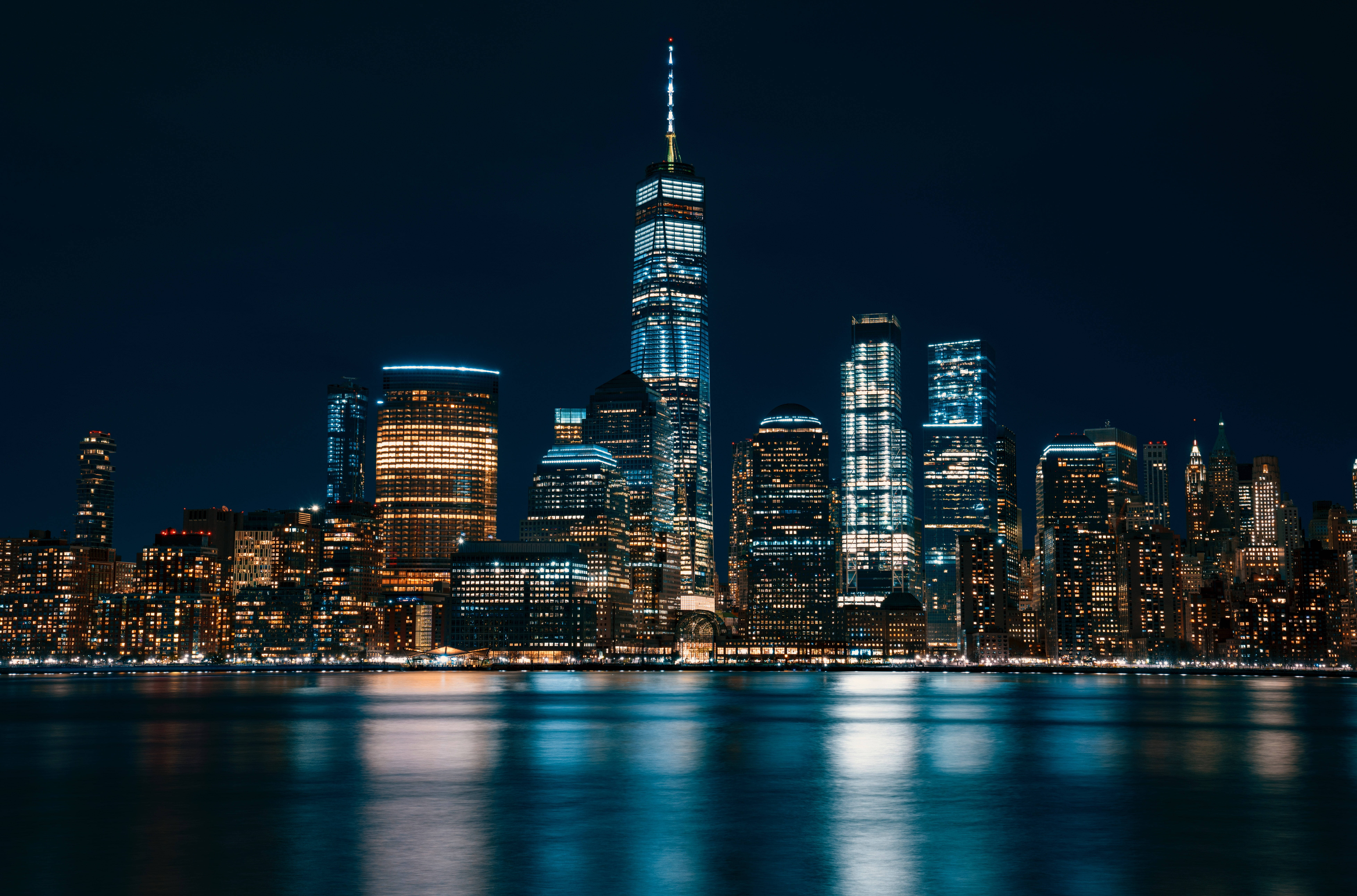 Skyscraper 桌布 壁紙 — 紐約天際線的絕美夜景，燈火通明的摩天大樓倒映在平靜的水面上。