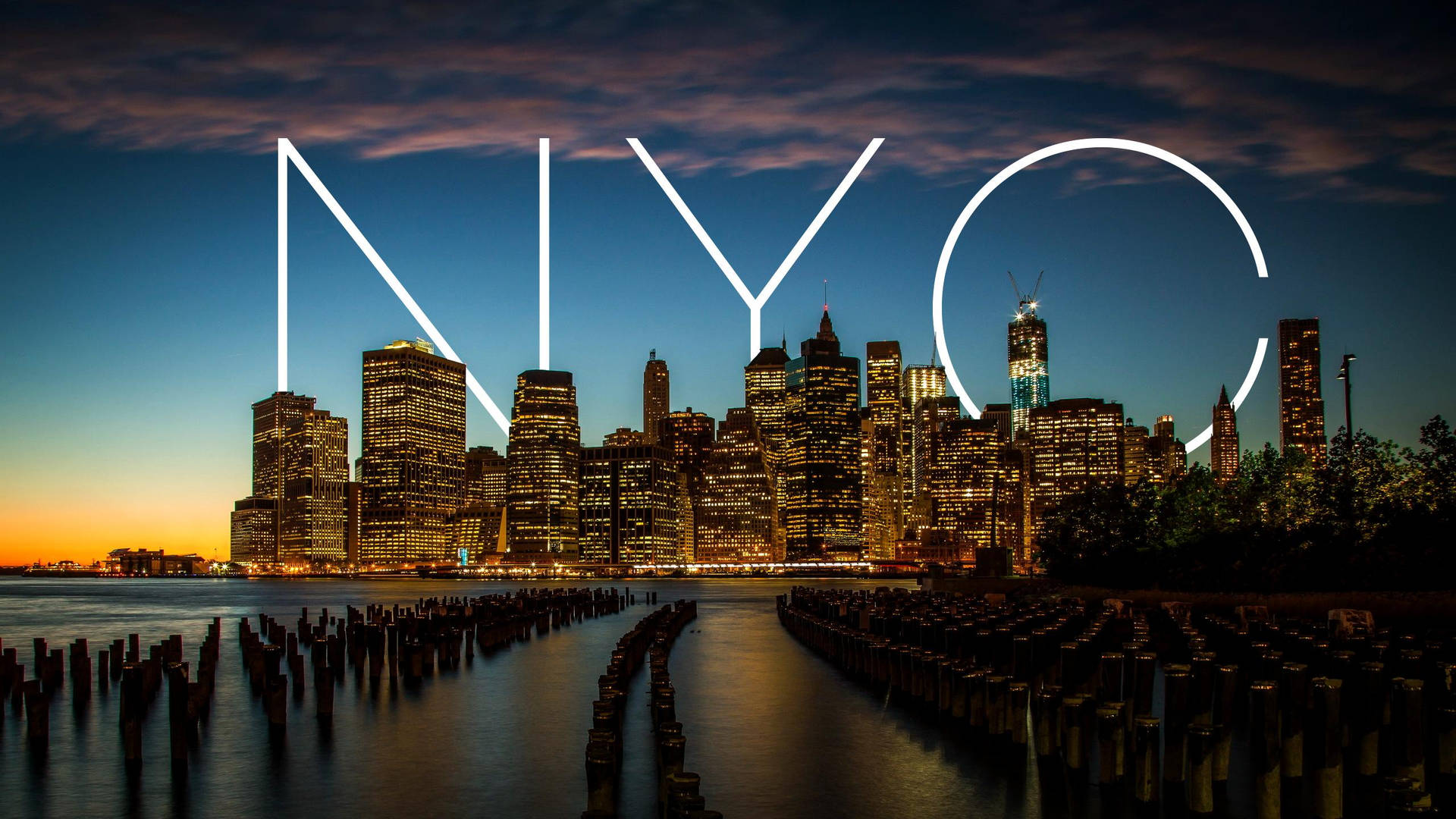 紐約市天際線在黃昏時分，發光的NYC字母在水面上。