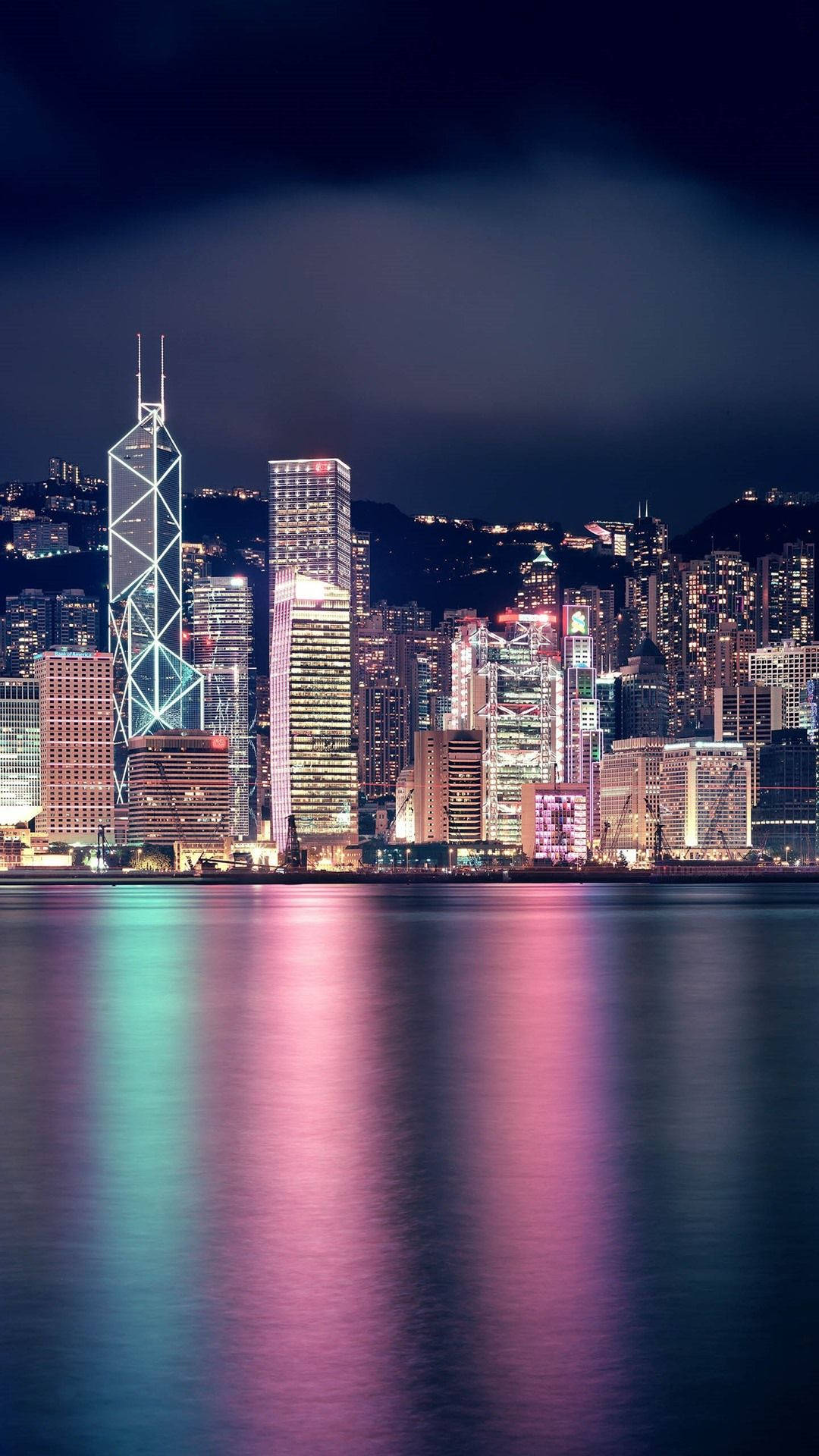 紐約市 iPhone X 海灣燈光 壁紙 — 充滿活力的夜景城市景觀，高聳的摩天大樓在平靜的水面上反射出五彩繽紛的燈光。