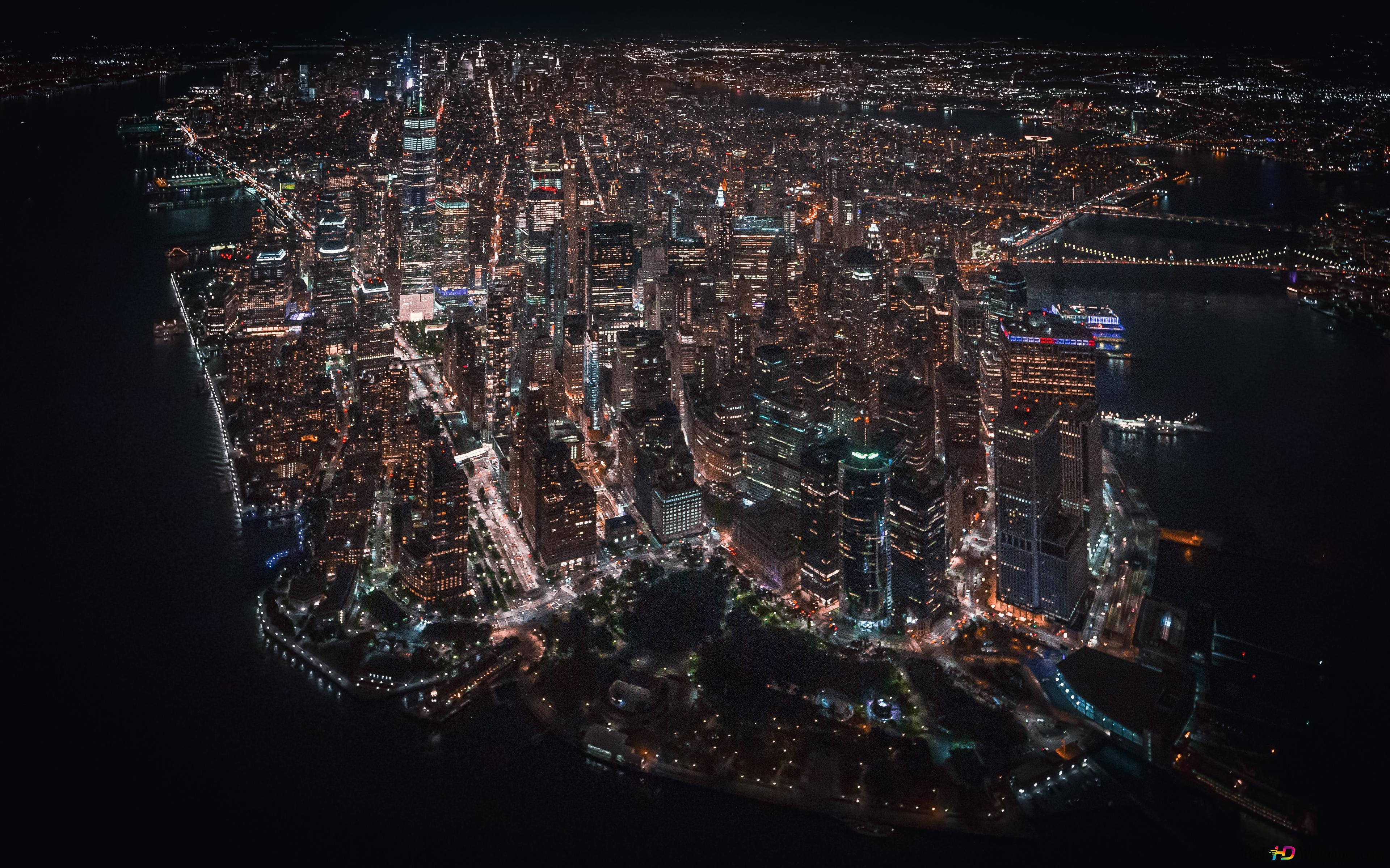紐約市壯觀的城市景觀 壁紙 — 廣闊城市景觀的夜間航拍，黑暗水面上有發光的摩天大樓和燈火通明的橋樑。