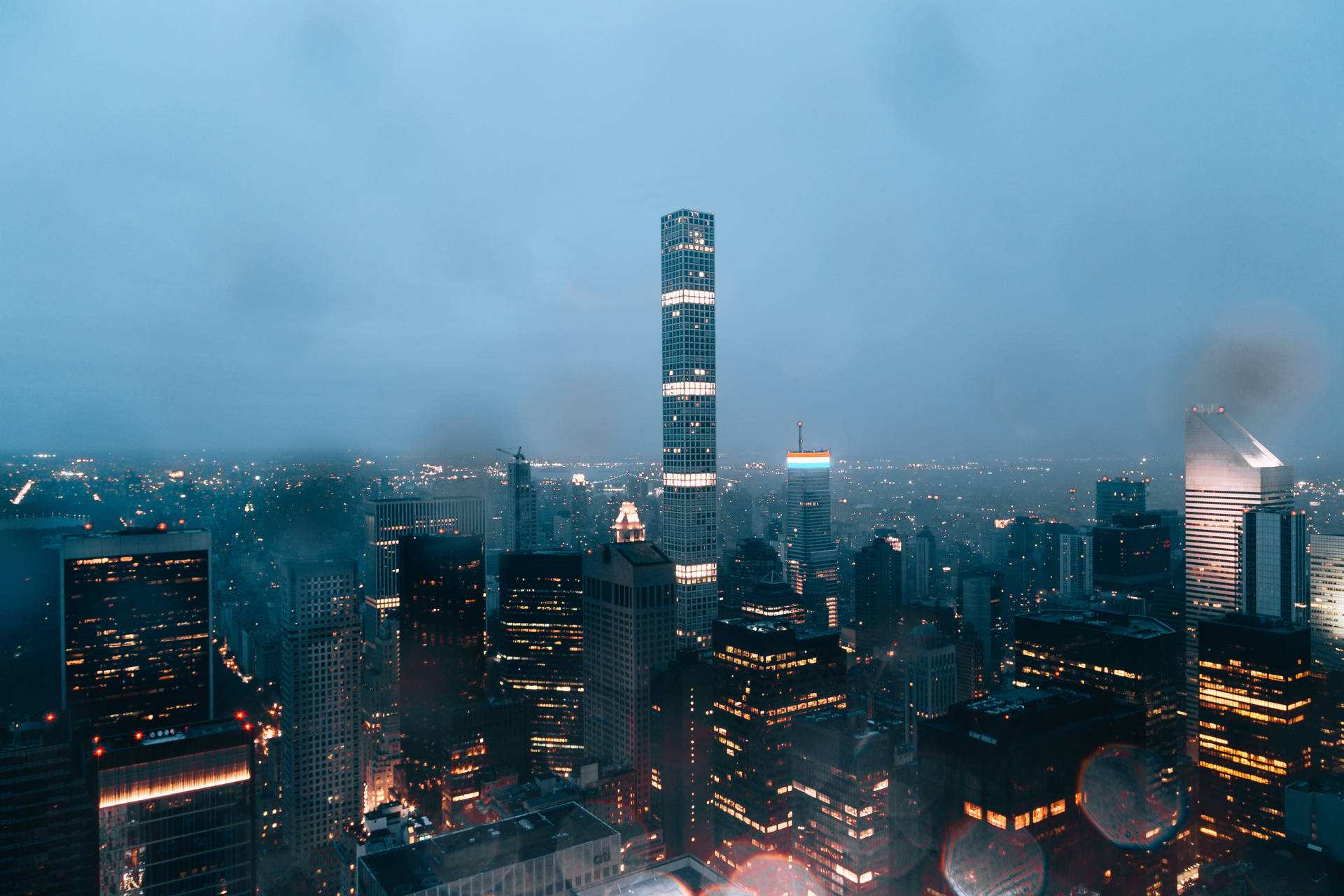 黃昏時分霧氣瀰漫的城市天際線，摩天大樓燈火通明。