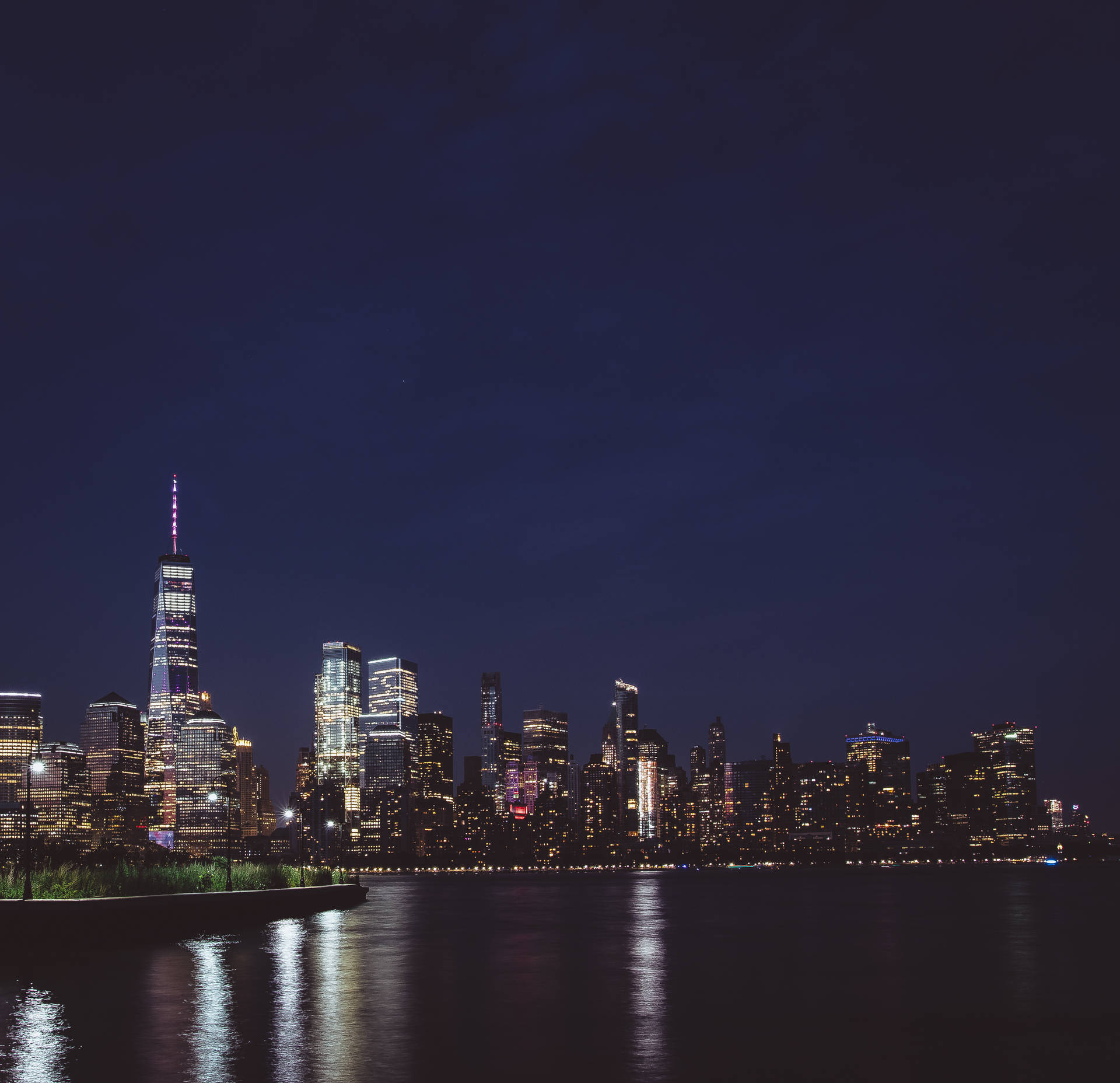 夜景城市景觀，閃爍的摩天大樓倒映在水中。