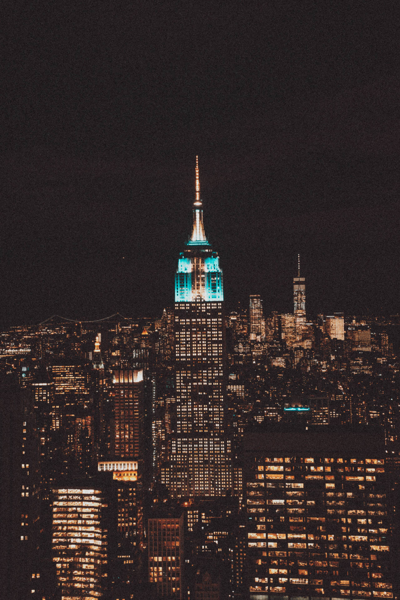 紐約市天際線的夜景，摩天大樓燈火通明，帝國大廈發出藍色光芒。