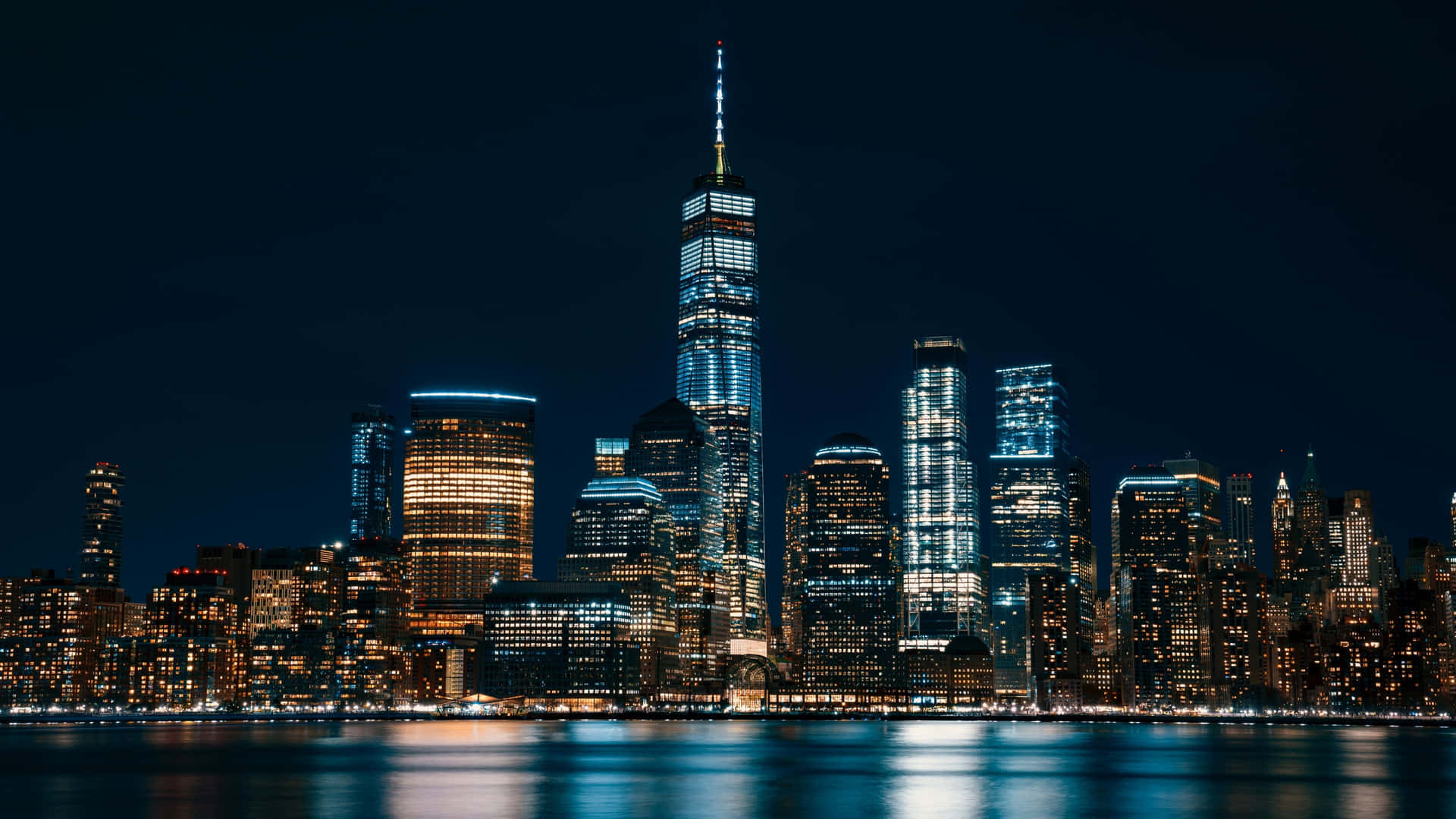 紐約市天際線的夜景，閃爍的摩天大樓和水面倒影。