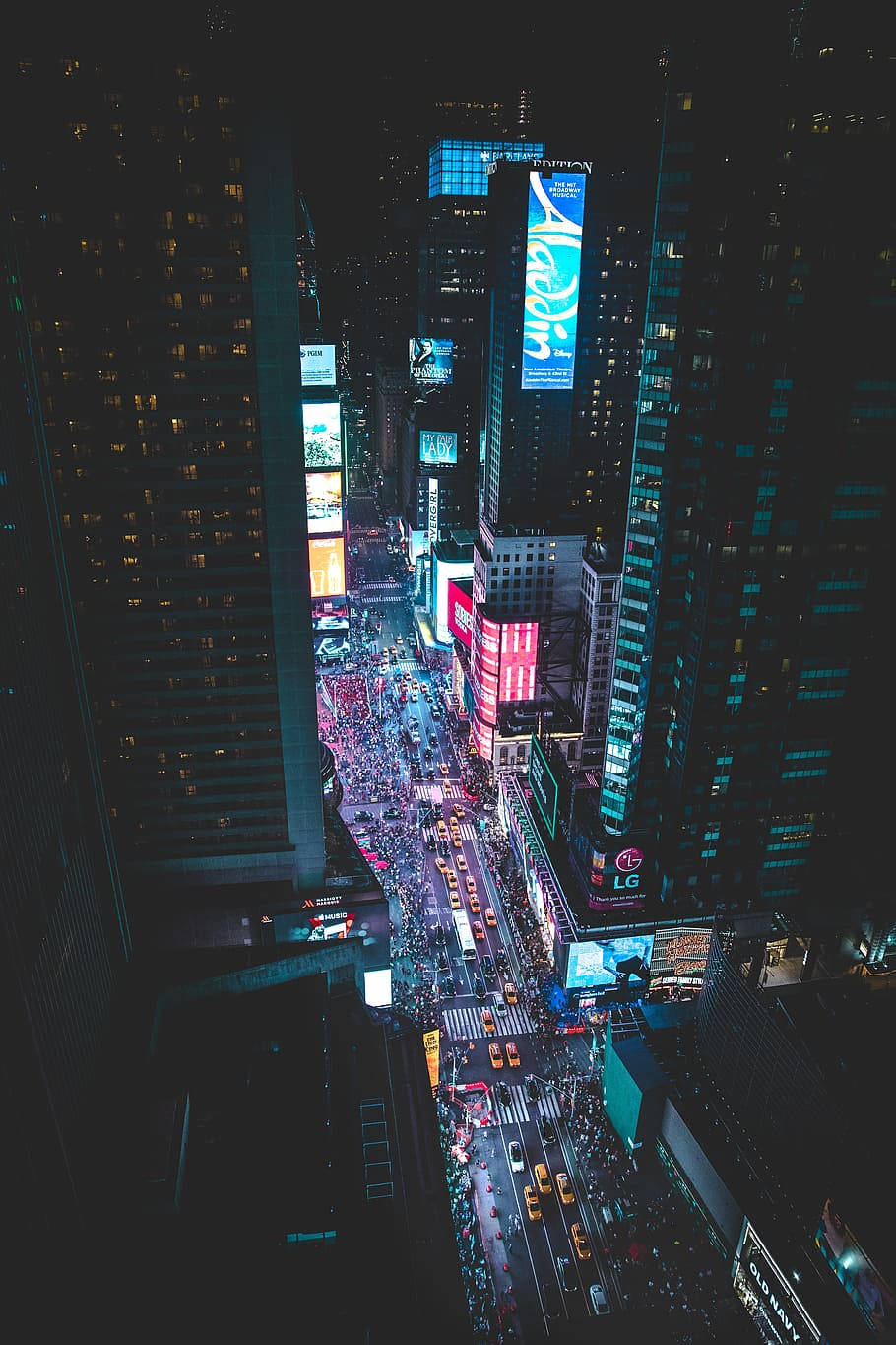 紐約市天際線在夜間水面上的倒影美景 壁紙 — 夜晚時代廣場的鳥瞰圖，下方有發光的廣告牌和擁擠的街道。