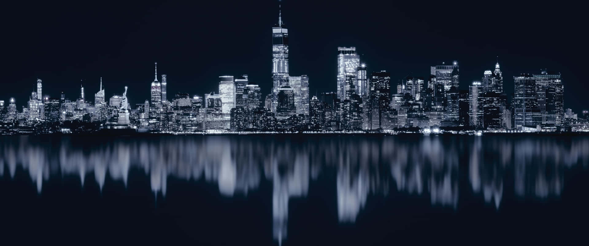 夜晚的紐約市天際線，建築燈光倒映在水中。