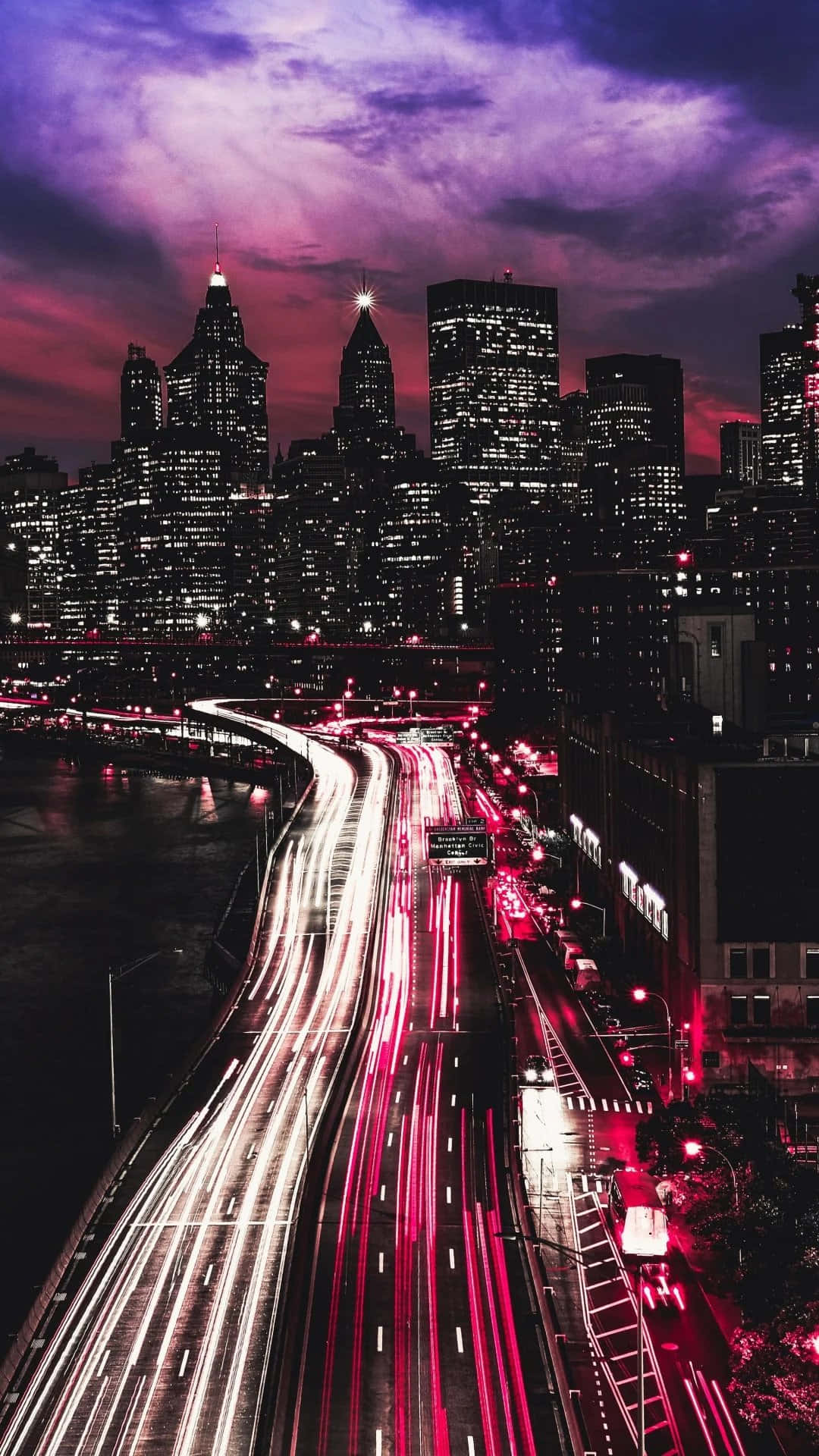 紐約市寧靜的夜間街景 壁紙 — 暮色中充滿活力的城市景觀，高聳的摩天大樓下橋樑上車流形成紅色和白色的光軌。