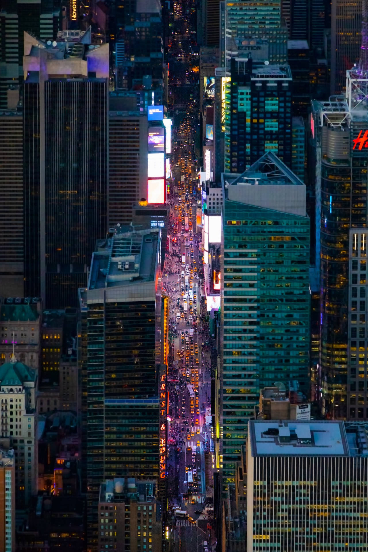 高聳摩天大樓之間，夜晚霓虹燈照亮城市街道的垂直鳥瞰圖。