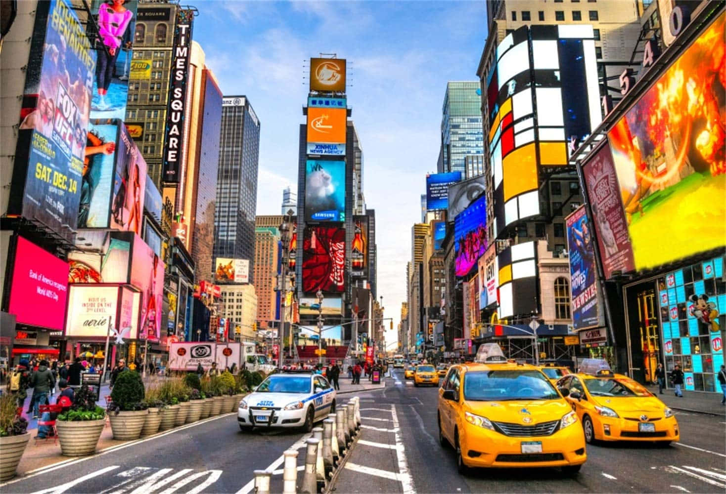 紐約市的自由與刺激 壁紙 — 充滿活力的時代廣場，高聳的廣告牌、霓虹燈和黃色出租車在清澈的藍天下熙熙攘攘。