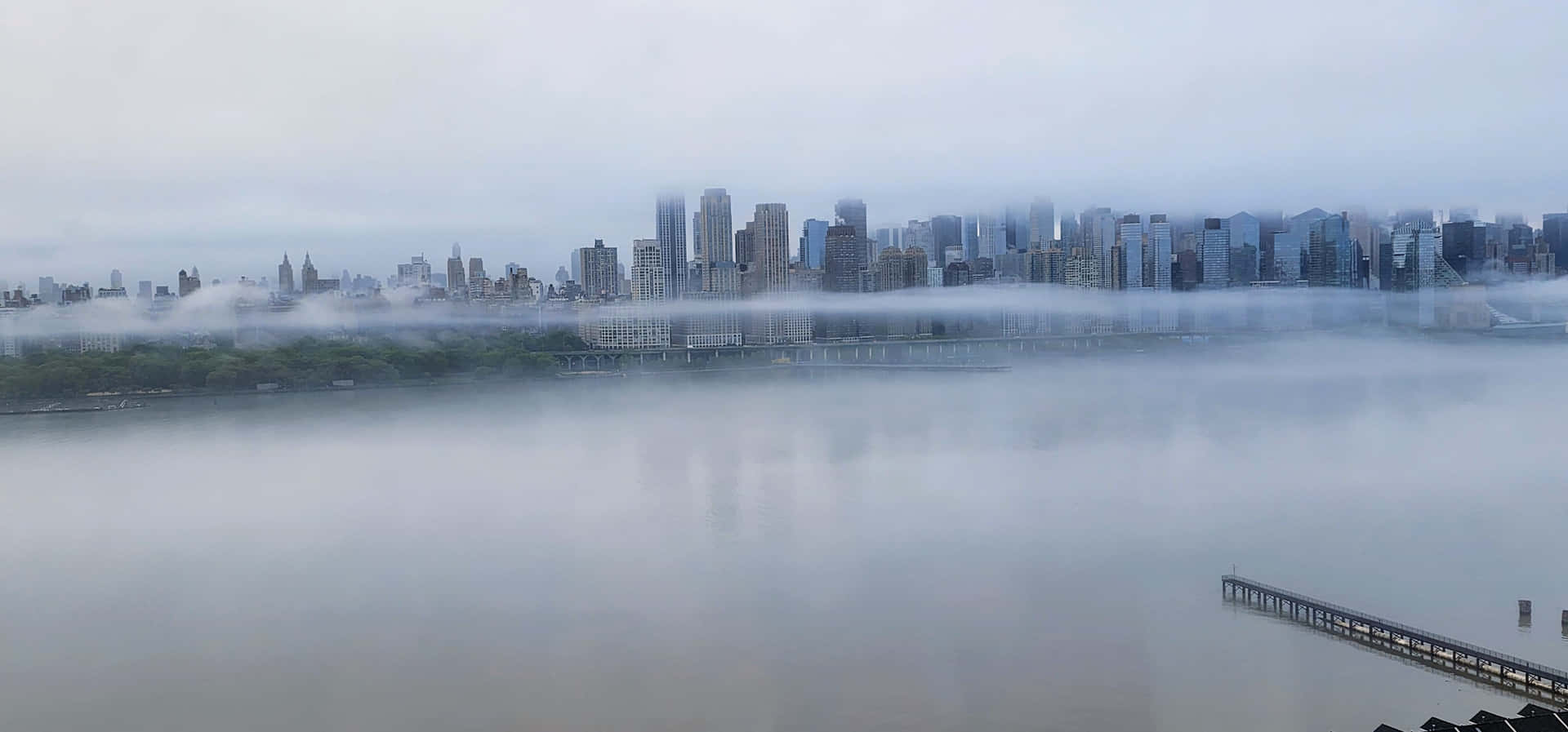 城市天際線從河流上的霧氣中升起，碼頭延伸入水中。