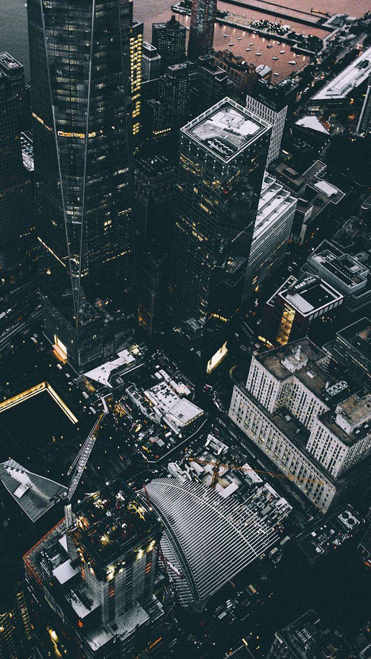 紐約市高樓 iPhone 壁紙 — 密集城市景觀的鳥瞰圖，夜晚高聳的摩天大樓和發光的窗戶。