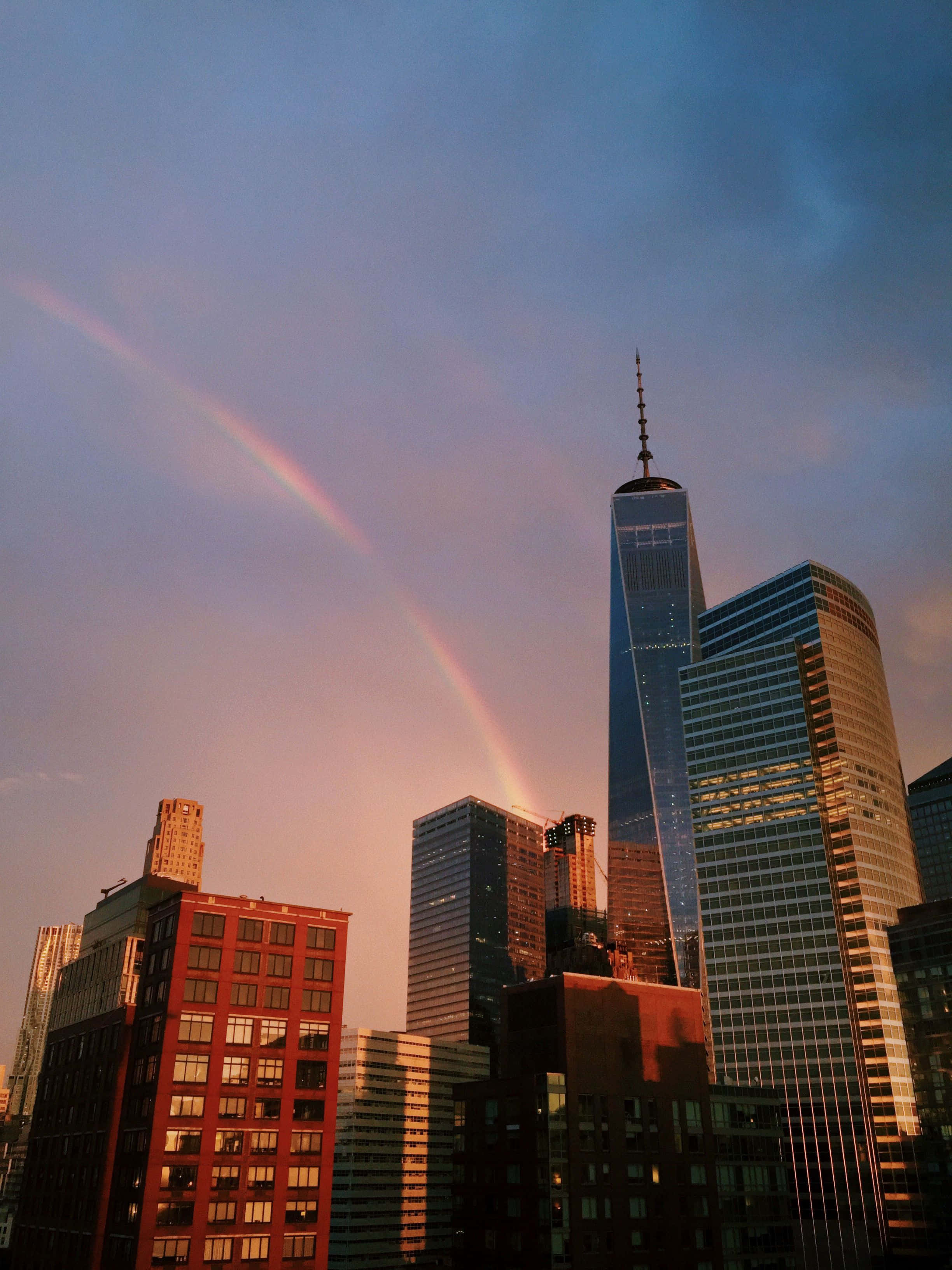 紐約時尚之美 壁紙 — 一道鮮豔的彩虹在色彩繽紛的日落時分橫跨 One World Trade Center 及周邊摩天大樓。