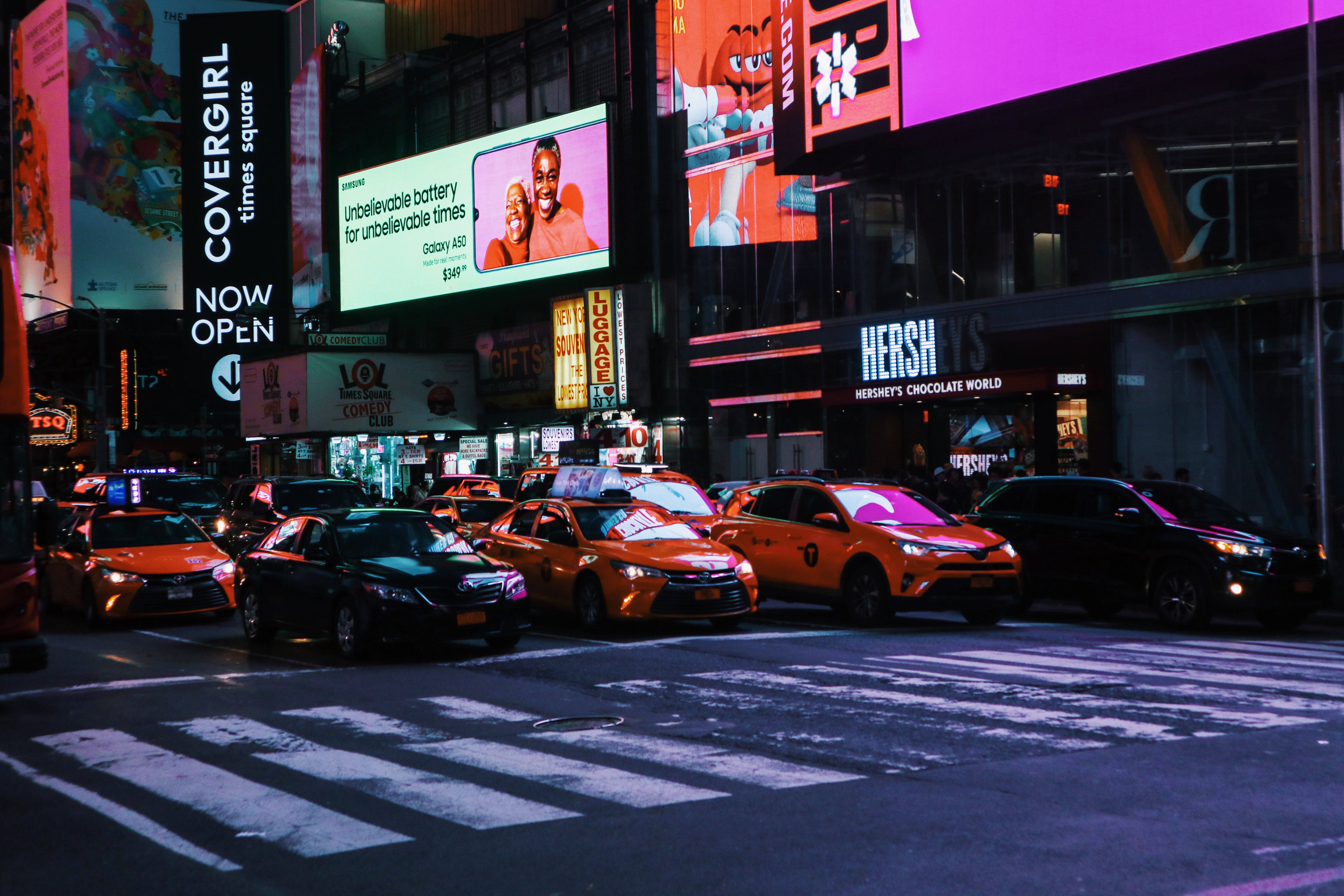 紐約時尚風格街頭車輛 壁紙 — 時代廣場充滿活力的夜間街景，閃爍的廣告牌和橙色出租車正在過馬路。
