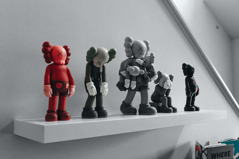 紐約藝術家 KAWS 的當代經典作品 壁紙 — 五個紅色、灰色和黑色的KAWS公仔站在白色層架上，背景是簡約的灰色牆壁。