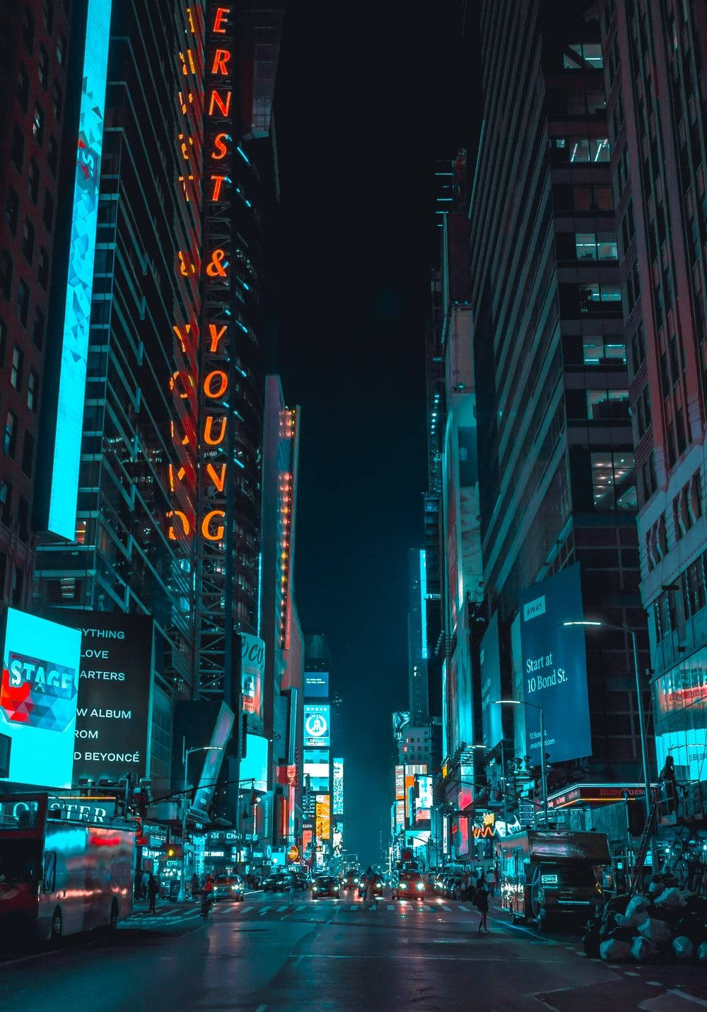 夜晚霓虹燈照亮的城市街道，高樓大廈和發光招牌映照在潮濕的路面上。