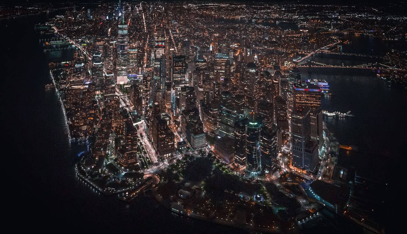 明亮城市夜景航拍圖，高樓大廈和河畔橋樑。