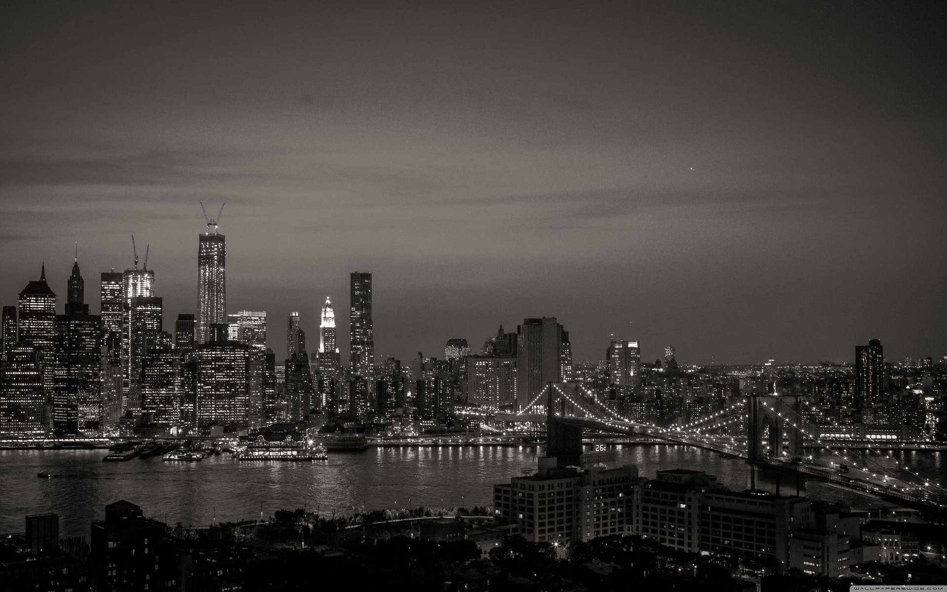紐約市天際線的夜晚黑白景觀，有燈光建築和橋樑。
