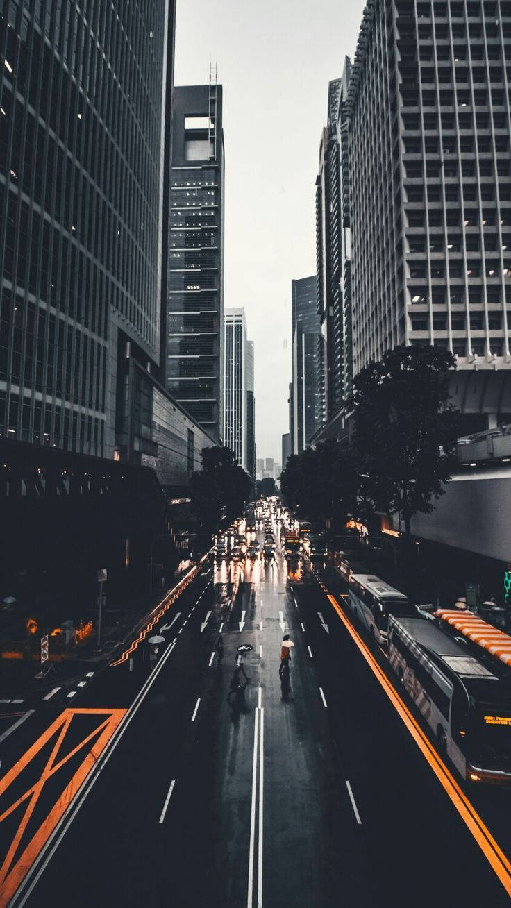 雨中的城市街道，高樓大廈和發光的橙色巴士專用道。