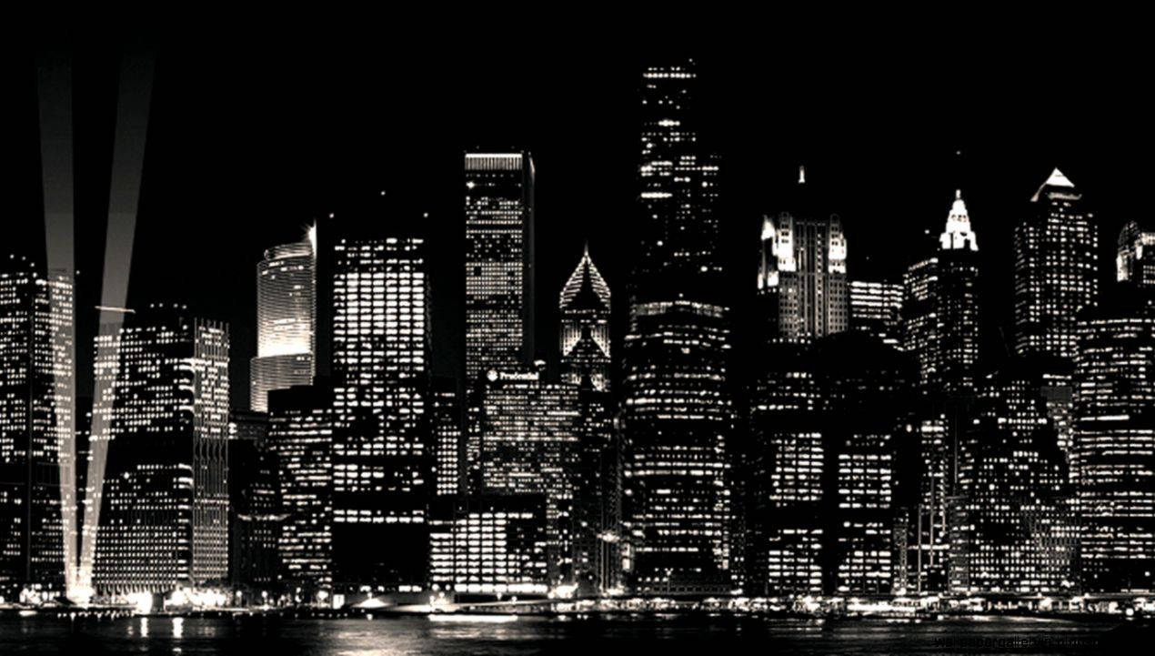 夜間黑白城市天際線，帶有燈光建築物和水面倒影。