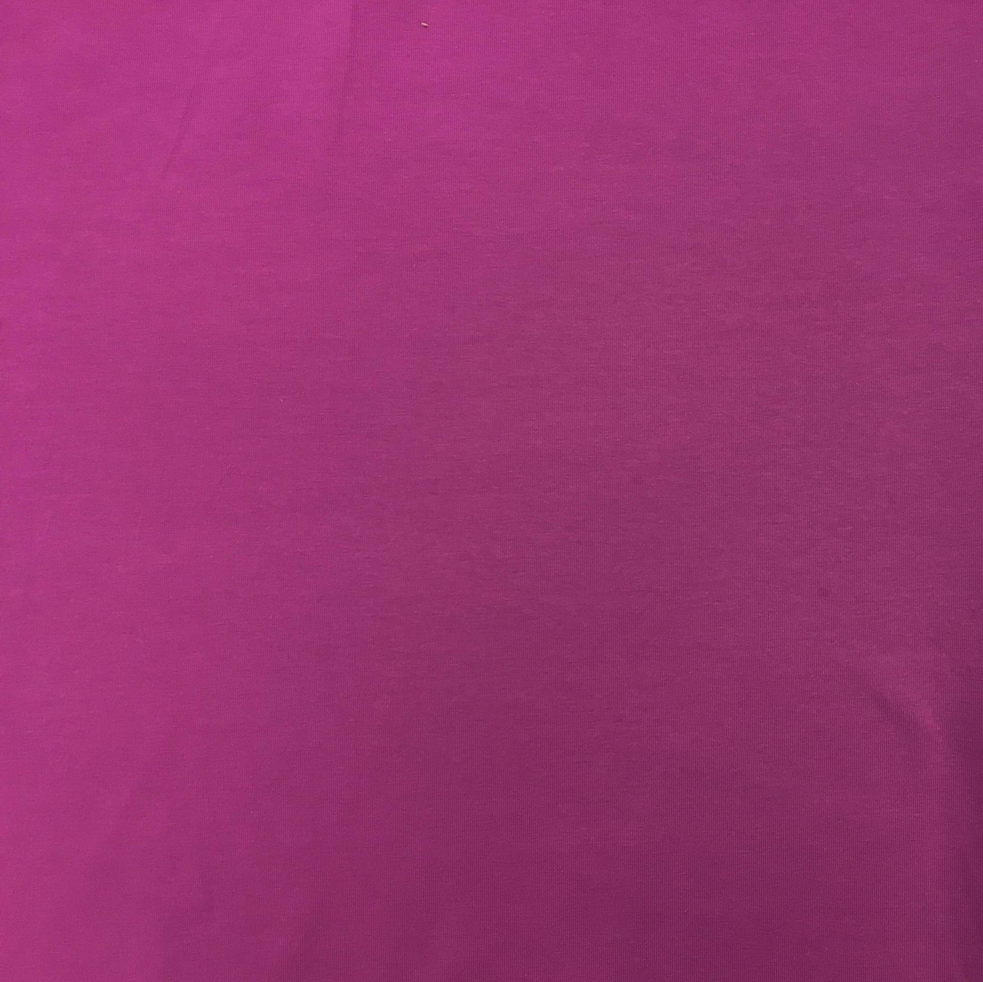 洋紅色布料嘅特寫，帶有細微紋理同柔和摺痕。