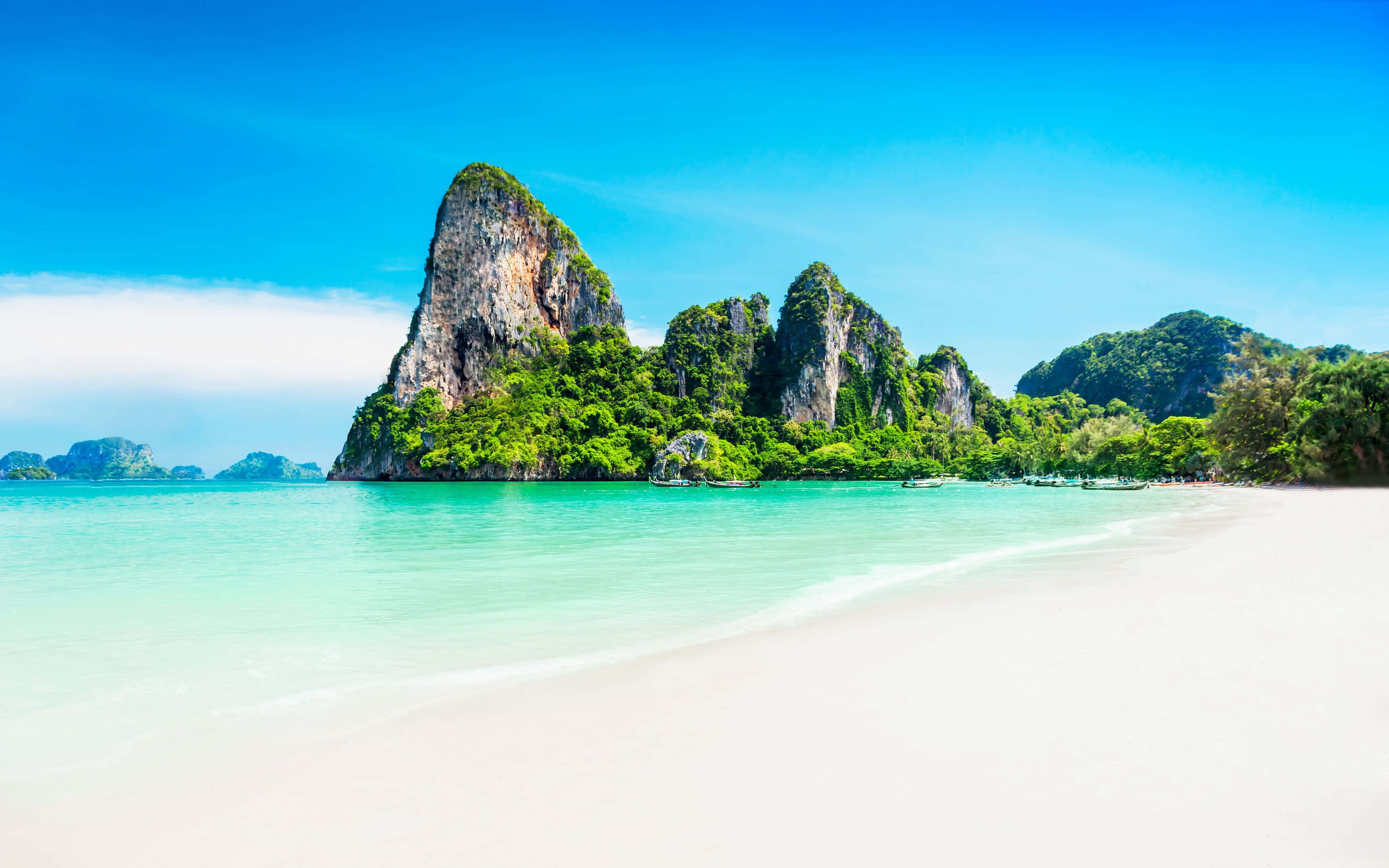 Thailand Beach 桌布 壁紙 — 純淨白沙灘與碧綠海水相接，在清澈藍天下，遠處鬱鬱蔥蔥的喀斯特島嶼巍然聳立。